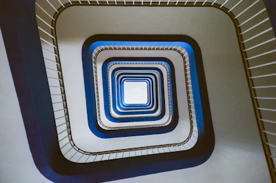 Looking down a modern spiral staircase with blue accents.