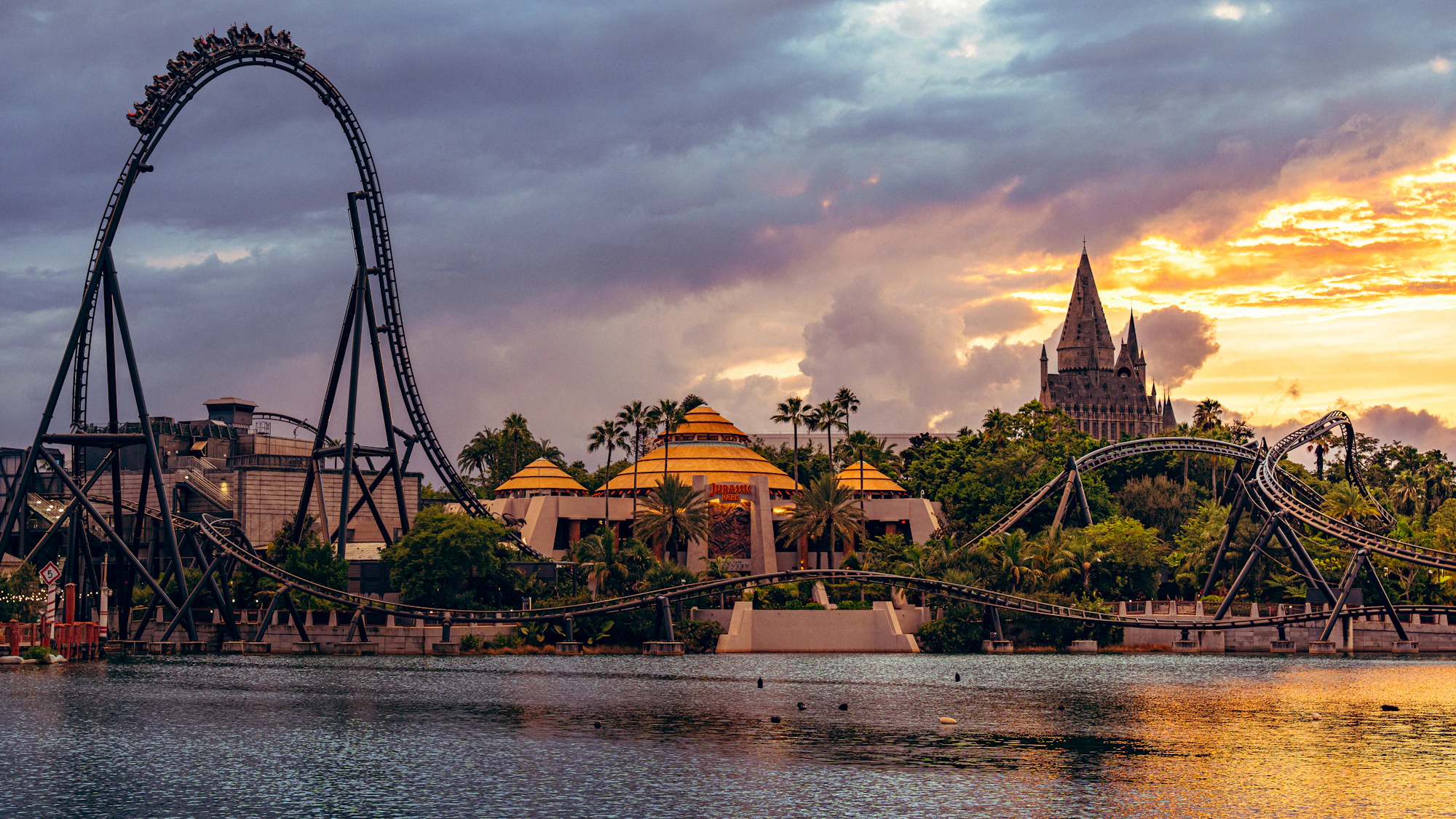 Castelo e montanhas-russas da Universal junto ao lago ao entardecer