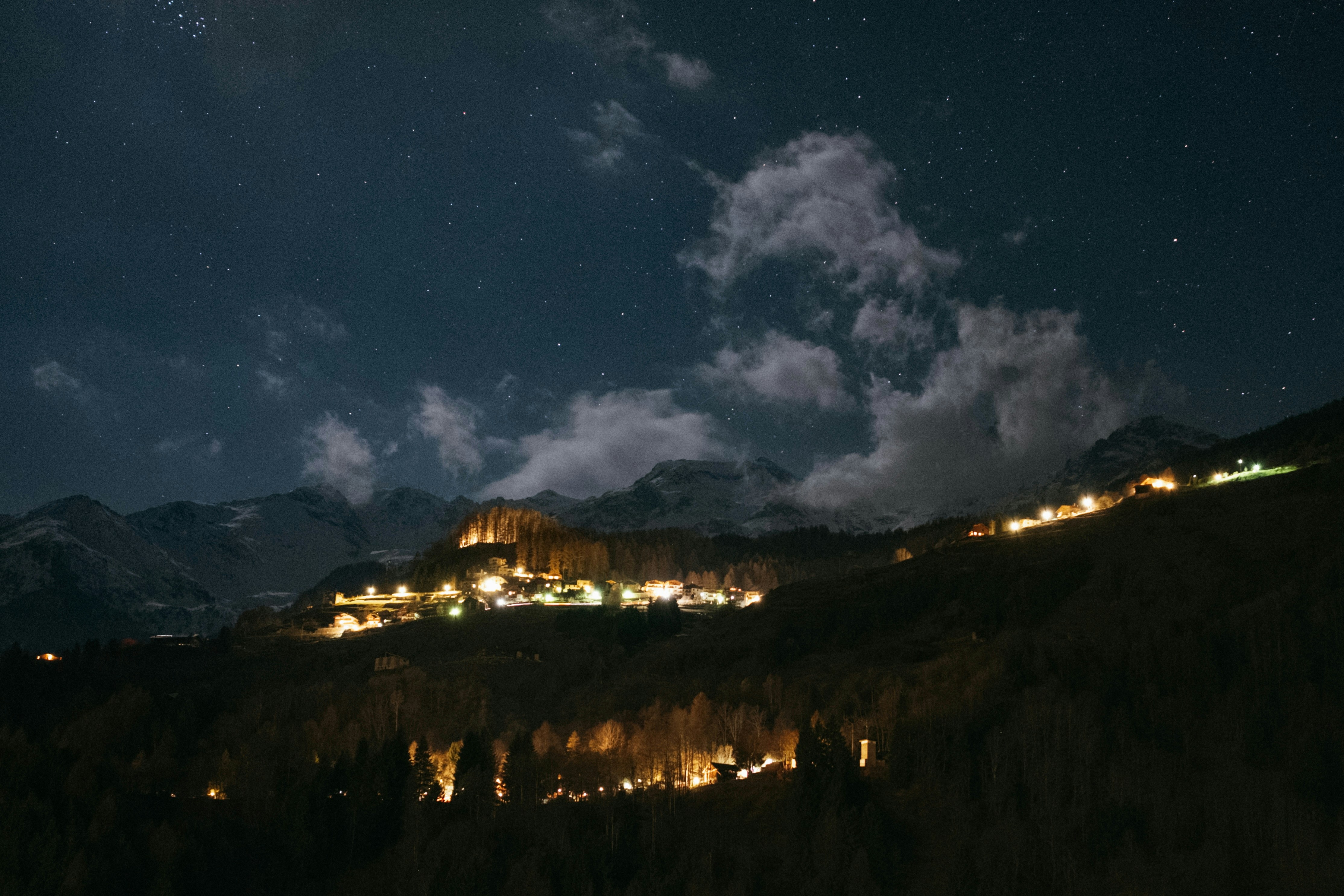 Un pueblo ilumina un paisaje montañoso por la noche.