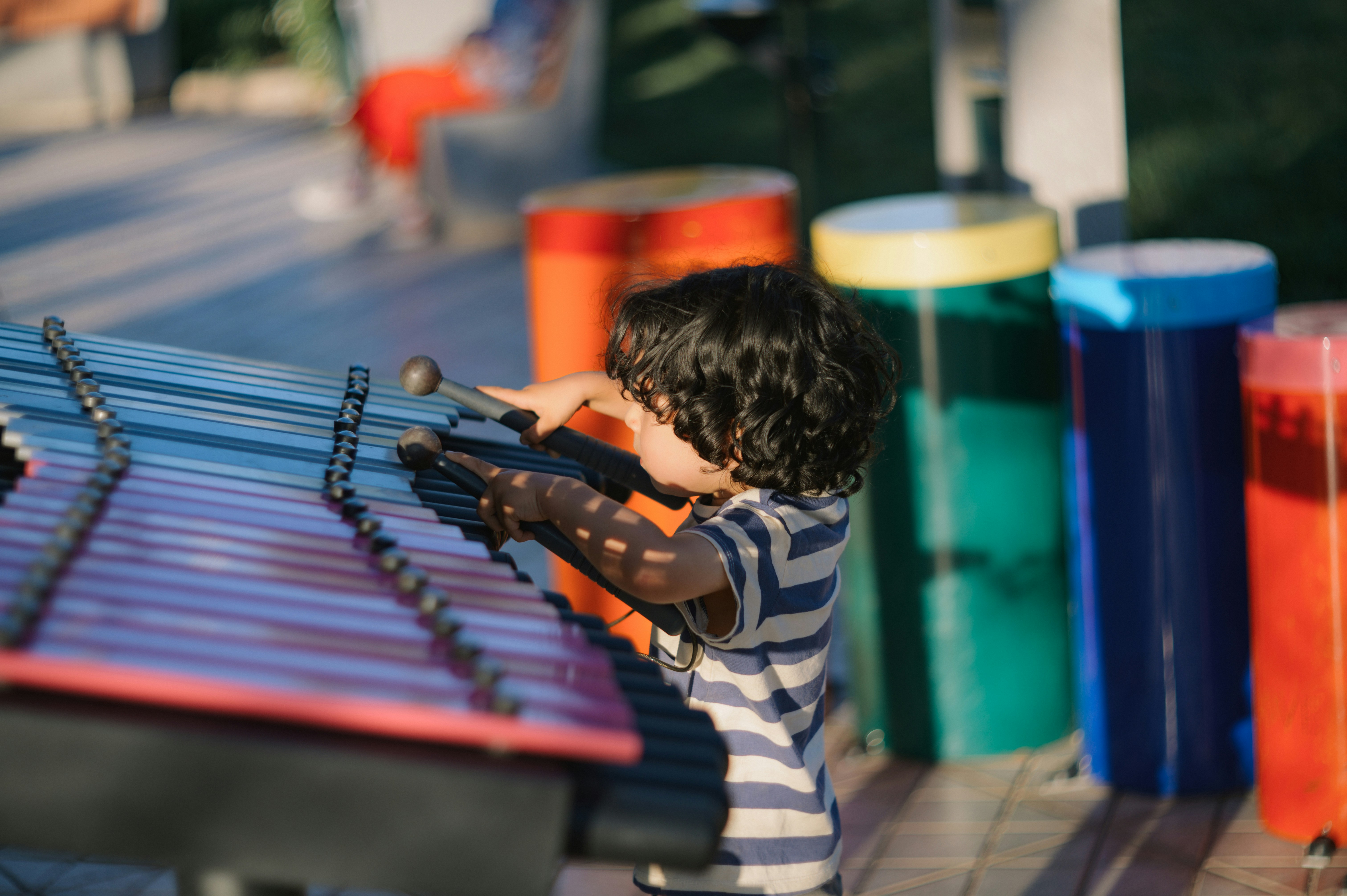 Un jeune garçon joue du xylophone en plein air.