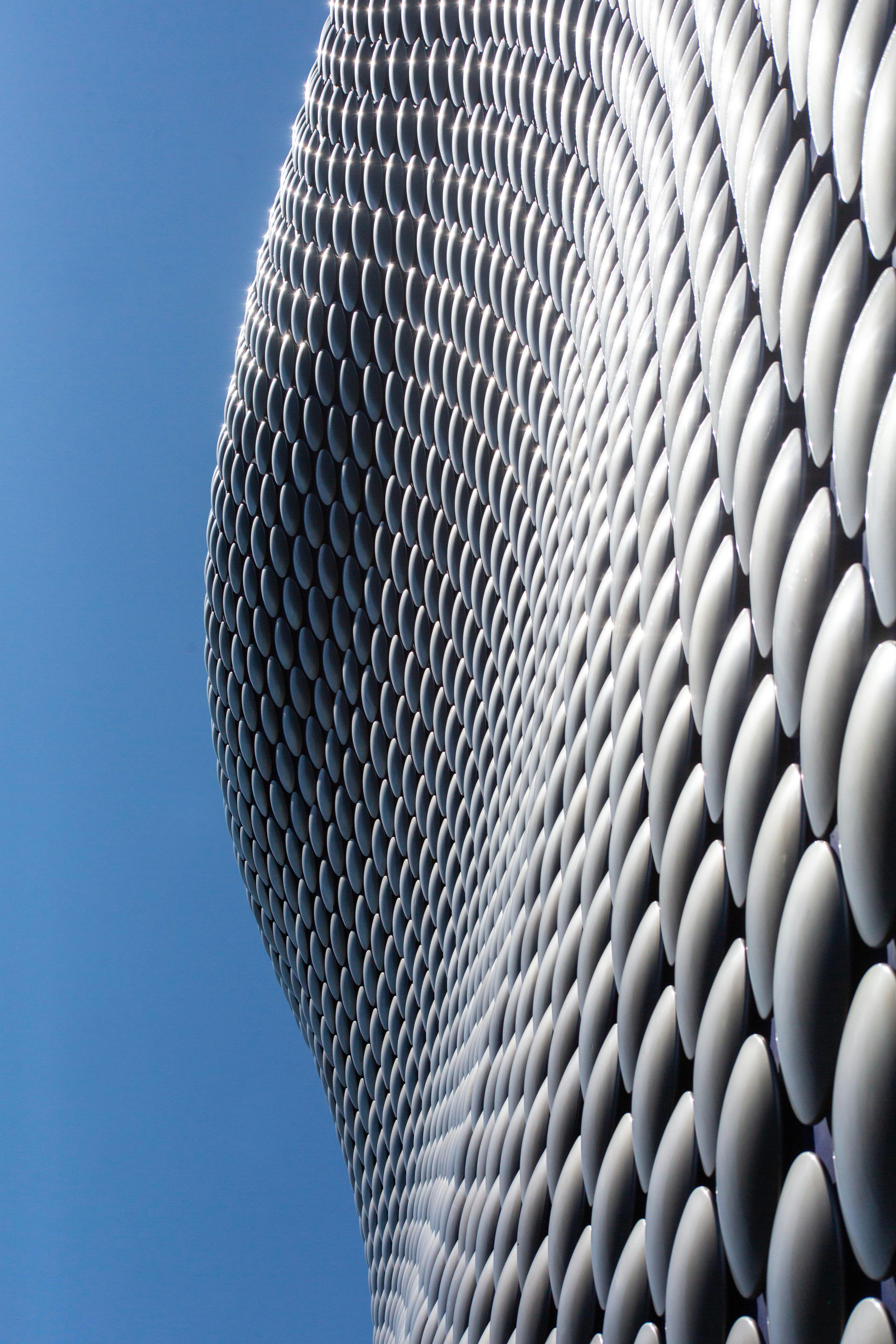 Facciata moderna dell'edificio con scaglie metalliche curve contro un cielo azzurro