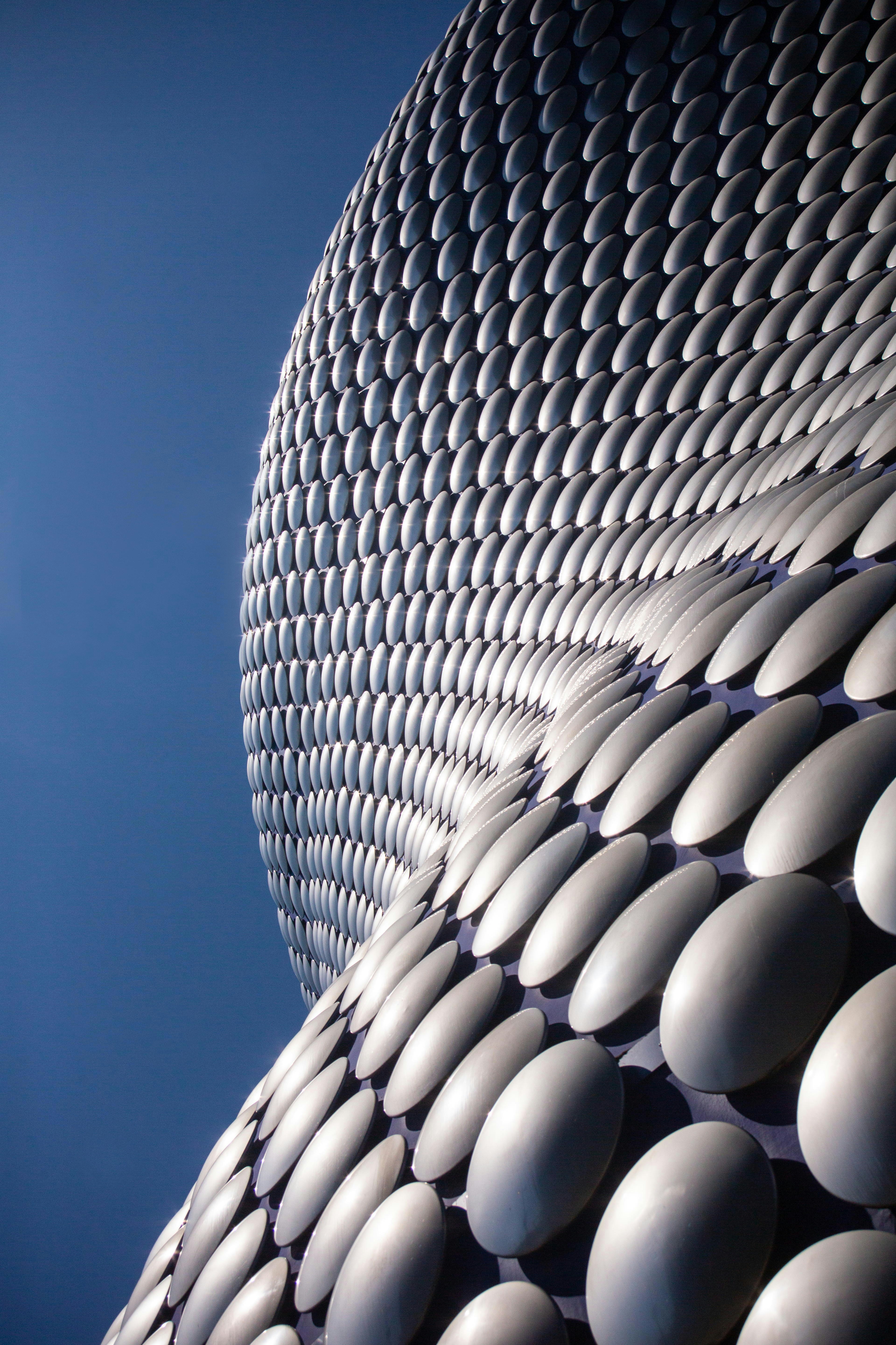 Modern building with curved metallic facade against blue sky