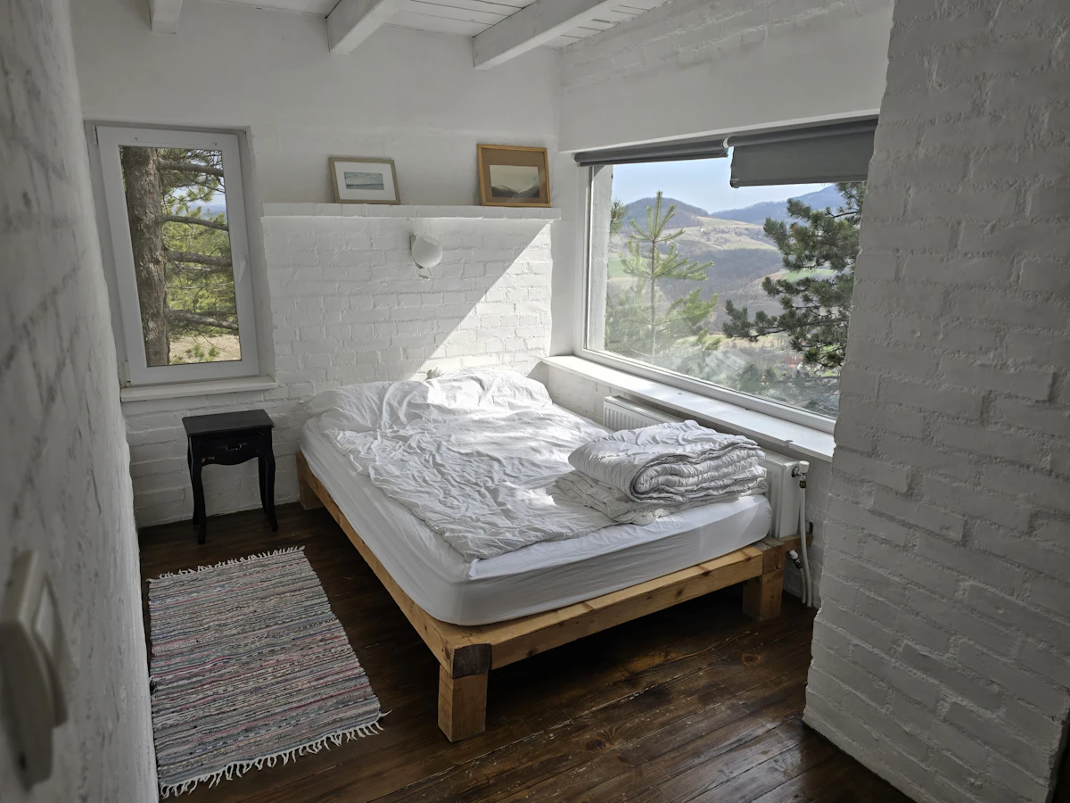 Simple homestay bedroom with a wide window looking out over the hills