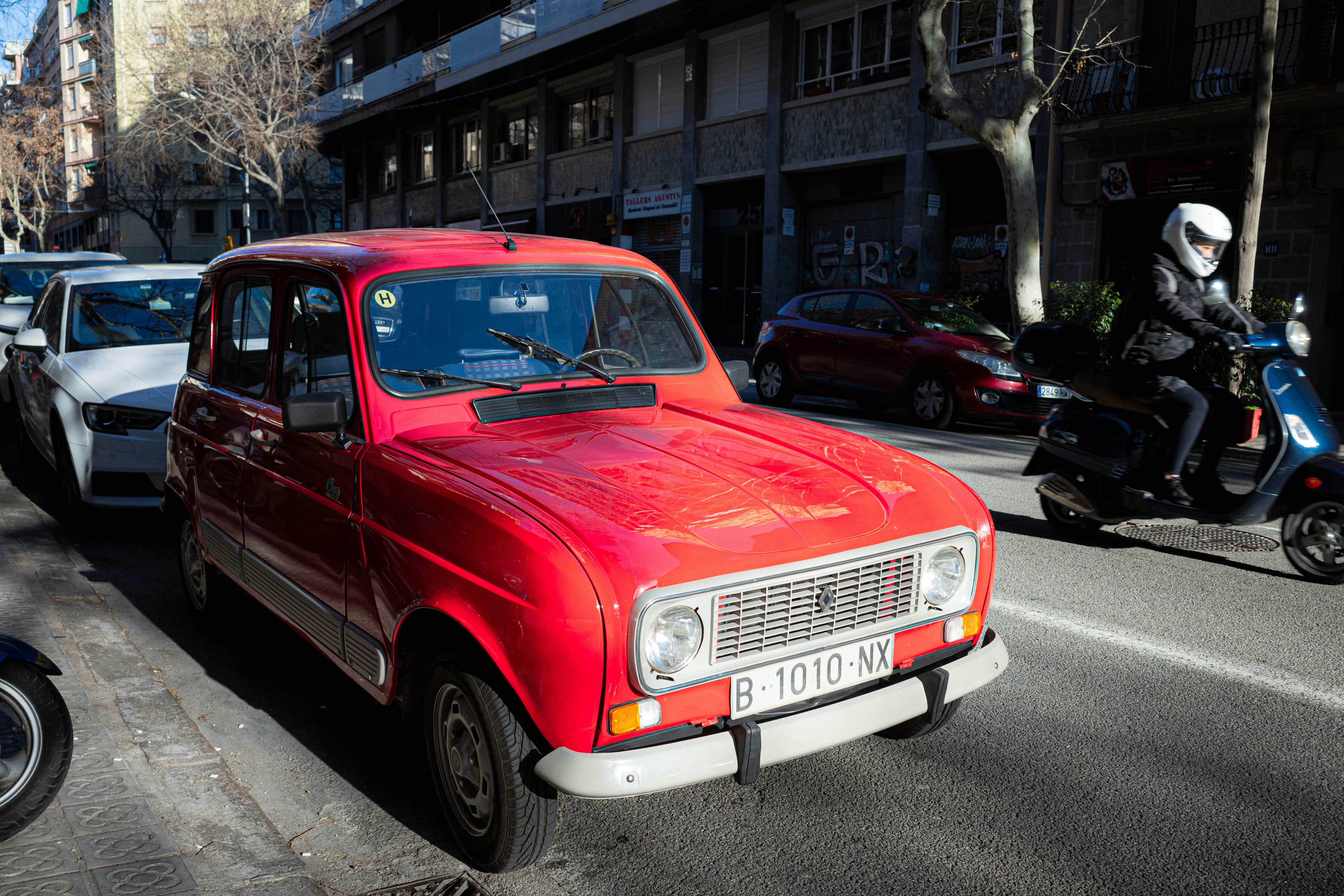 Fotomural A bright red vintage car parked on a city street