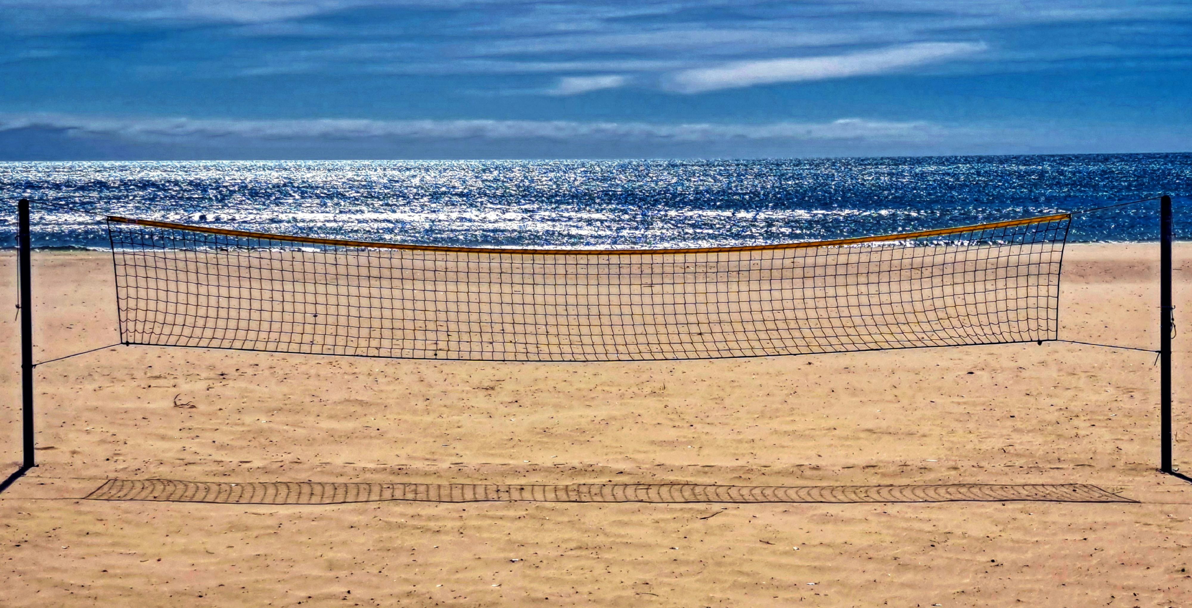 Filet de beach-volley sur une plage de sable avec un fond océanique