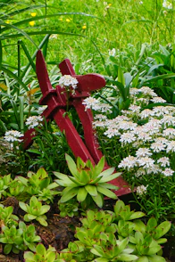 Red anchor resting amongst green plants and white flowers