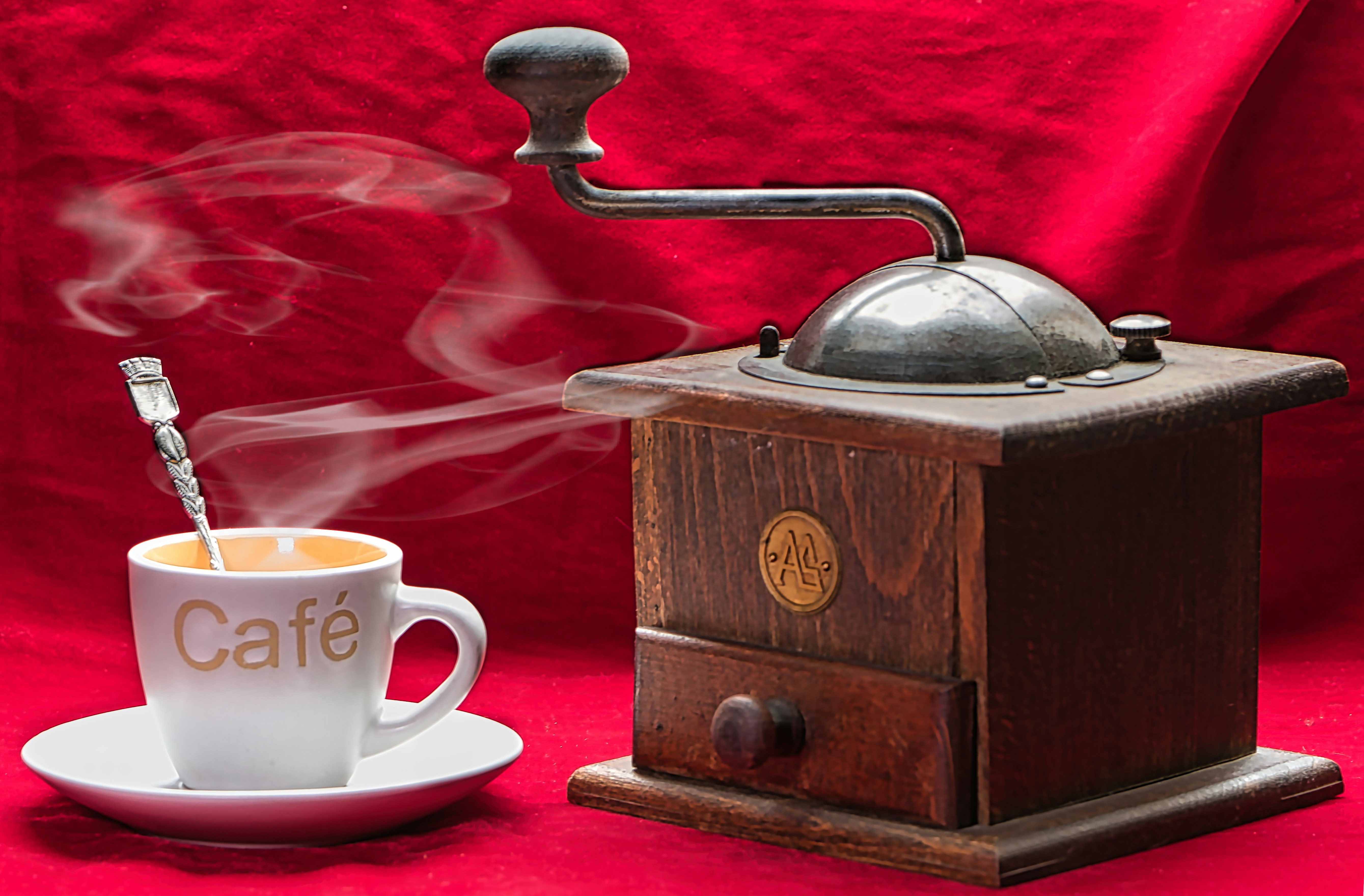 Taza de café humeante junto a un molinillo de café antiguo.