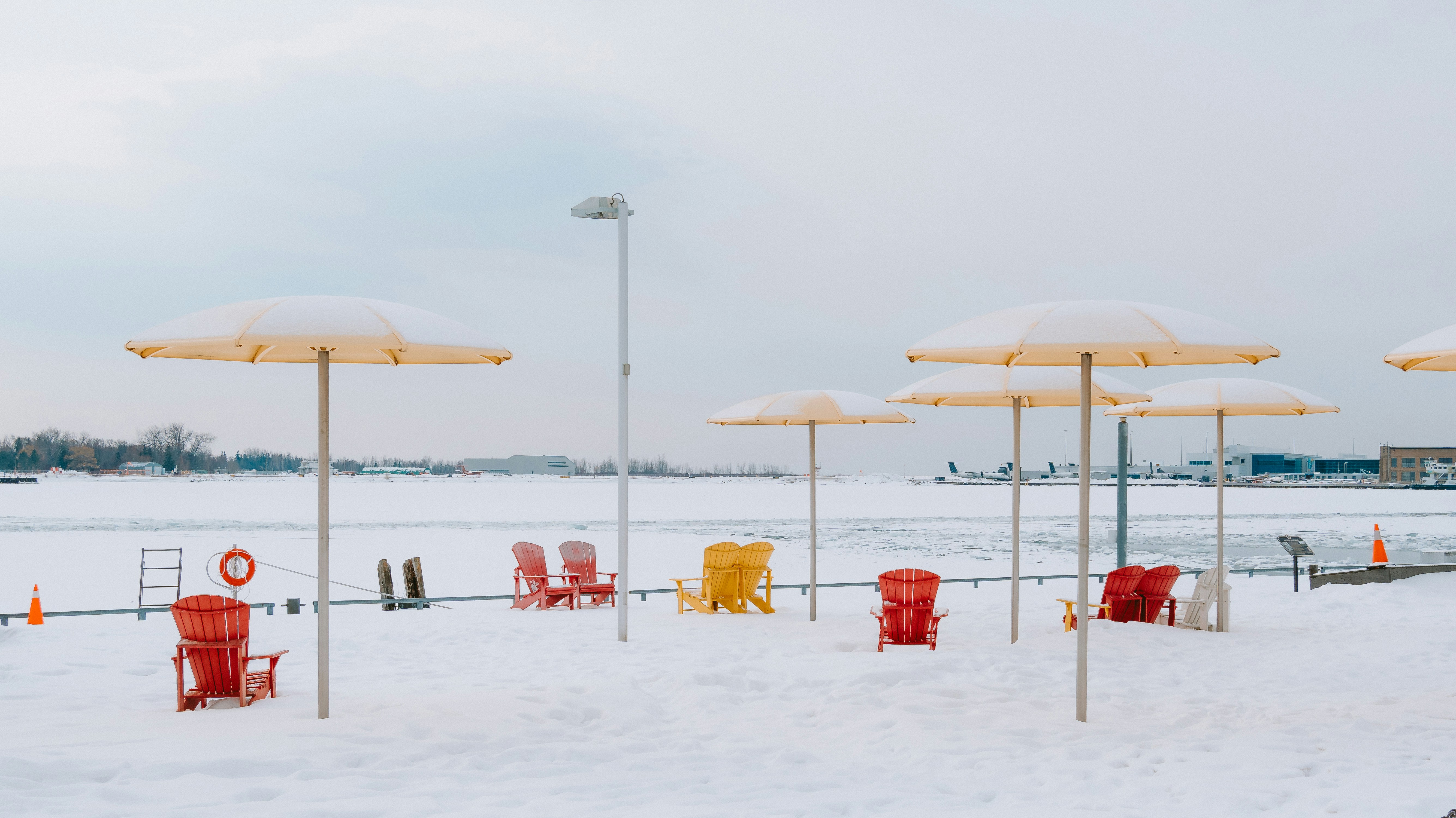 Strandstühle und mit Schnee bedeckte Strandstühle und Sonnenschirme