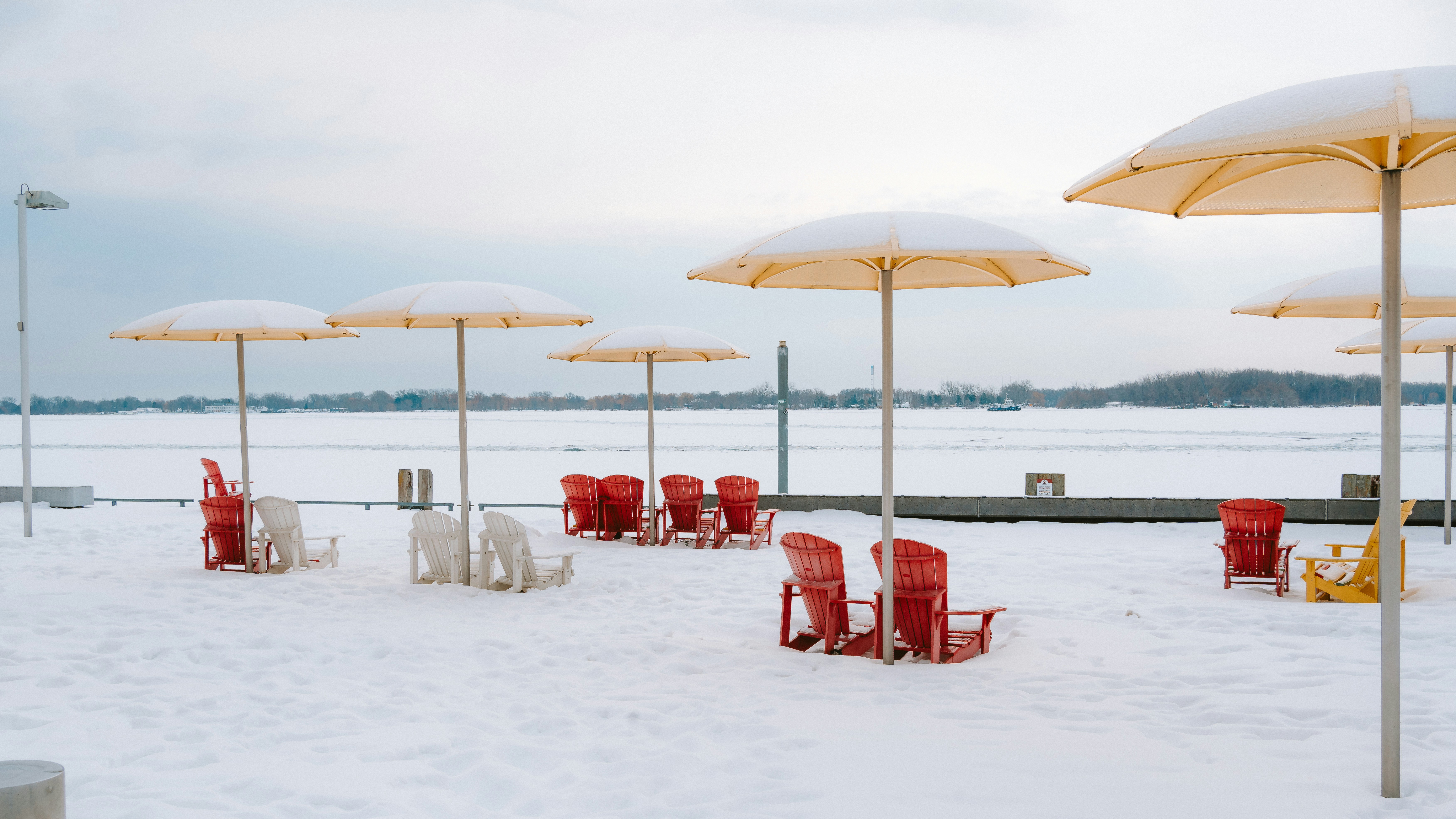Leere Strandstühle und Schirme, die mit Schnee bedeckt sind
