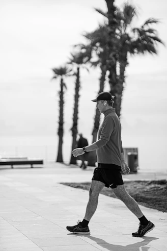 Man walking on a sunny day with palm trees.