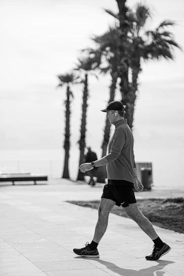 Man walking on a sunny day with palm trees.