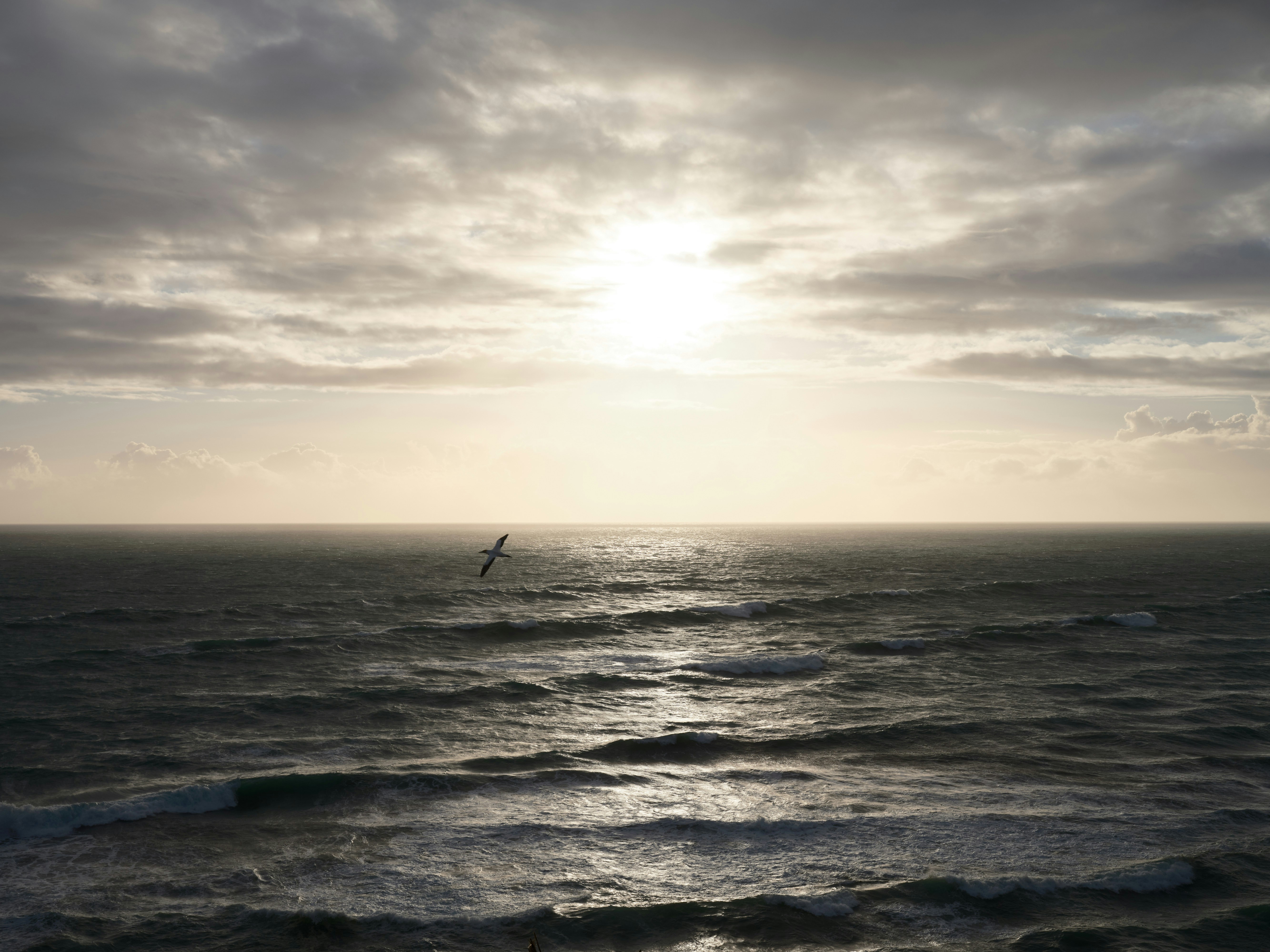 Sunlight breaks through clouds over a choppy ocean.