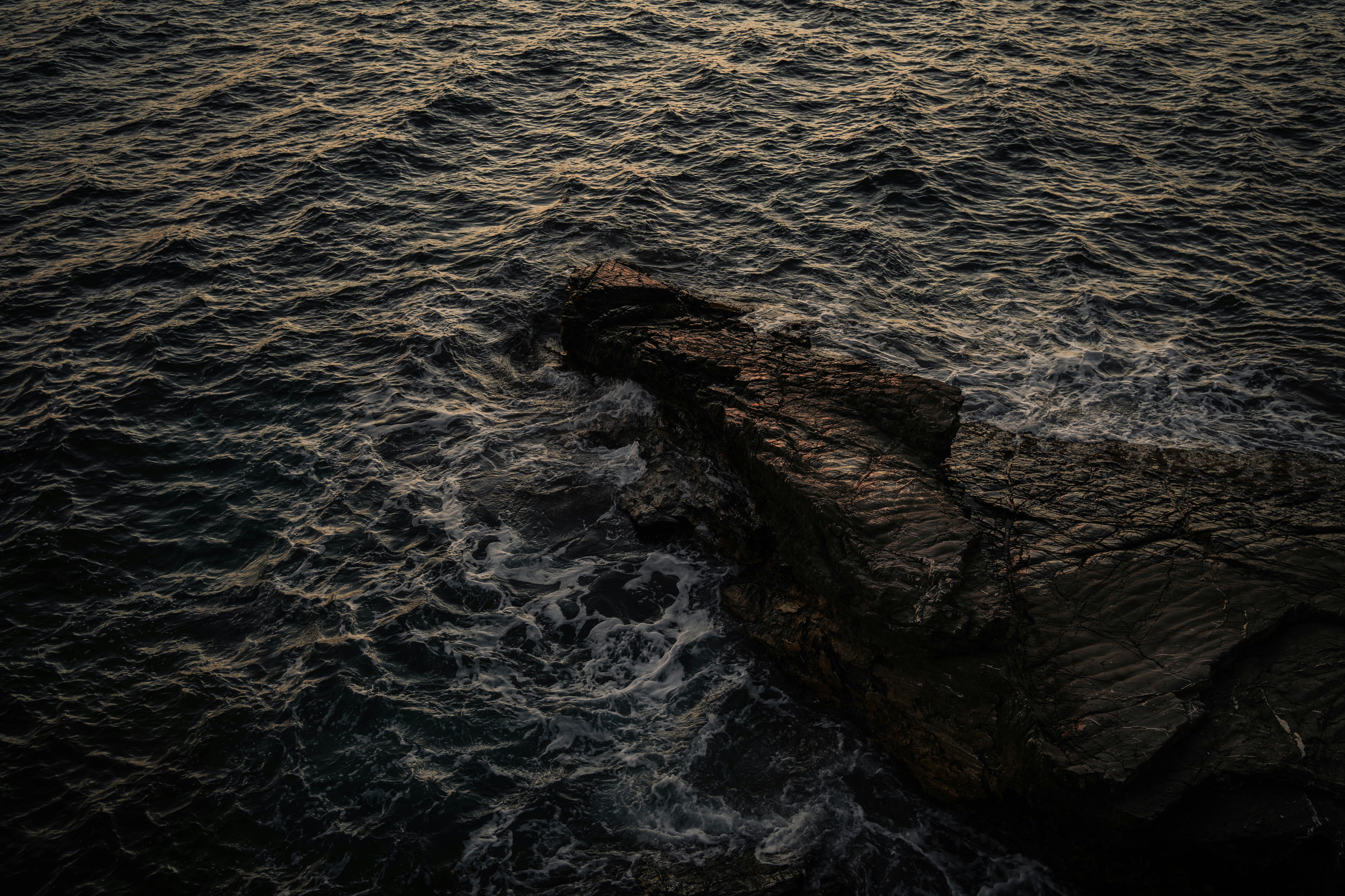 Waves crashing against a rocky coastline at dusk
