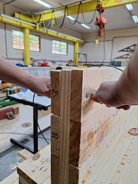 Hands assembling wooden beams with metal fasteners