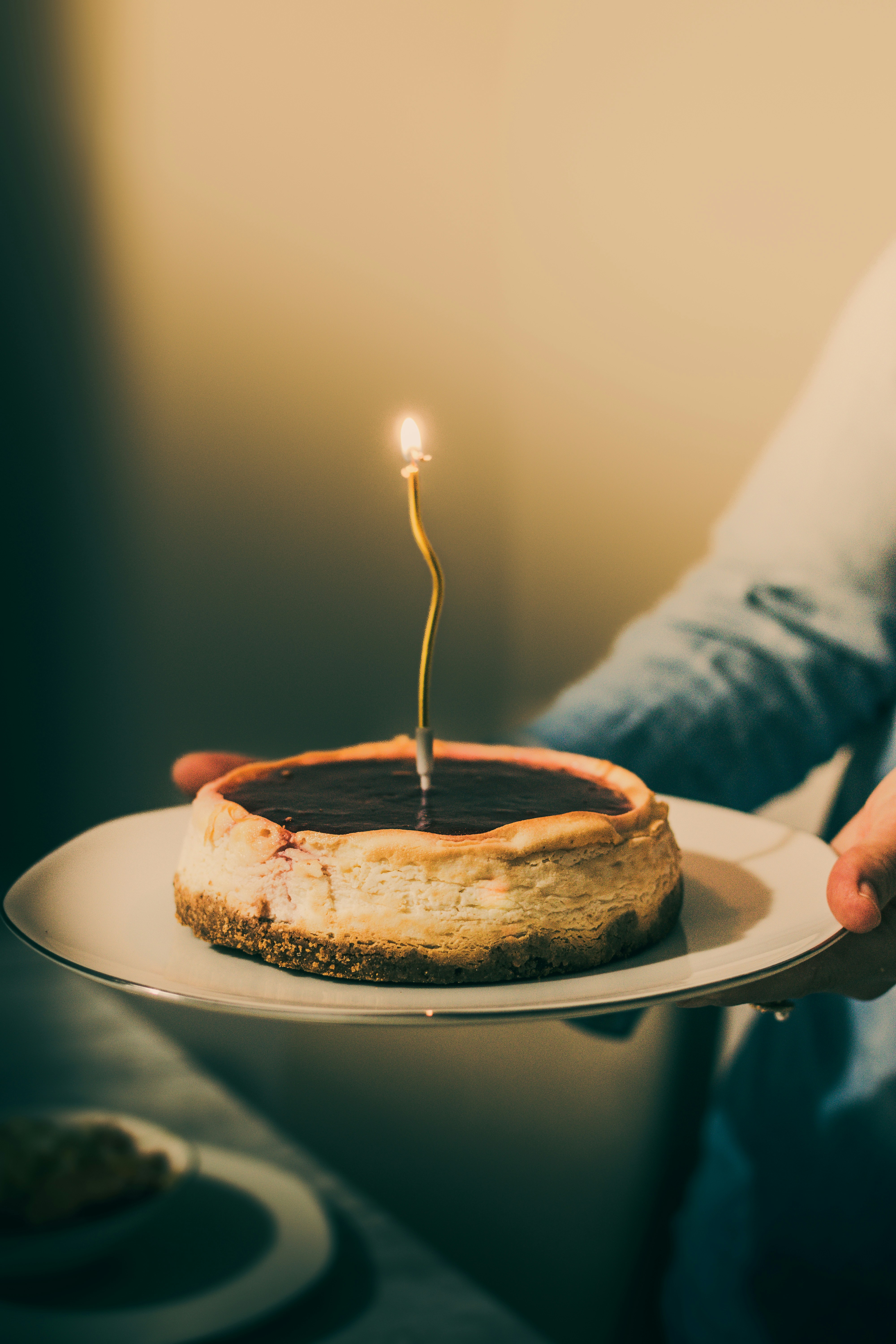 Um cheesecake com uma única vela acesa em um prato