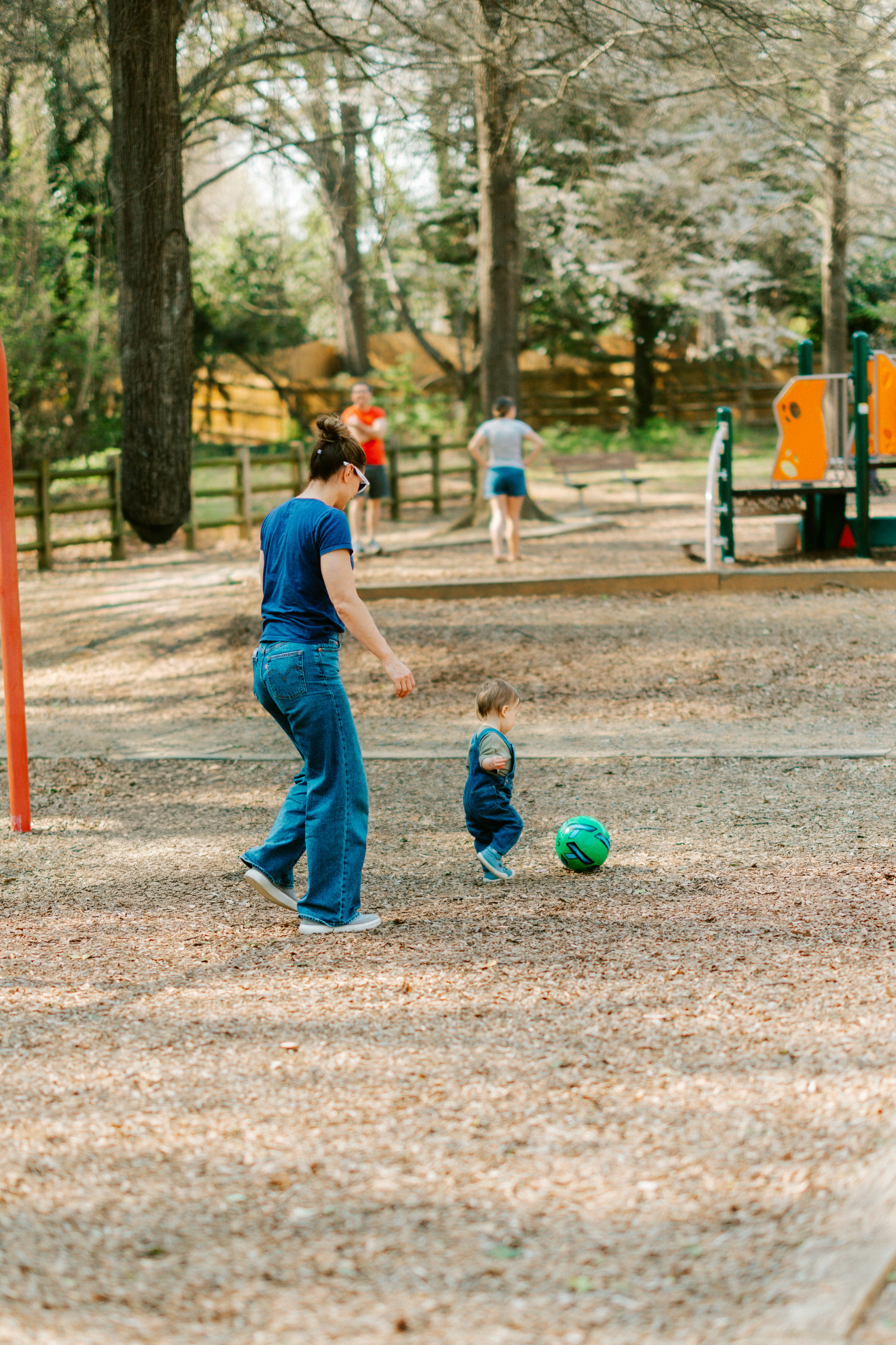 Ibu dan anak bermain sepak bola di taman.