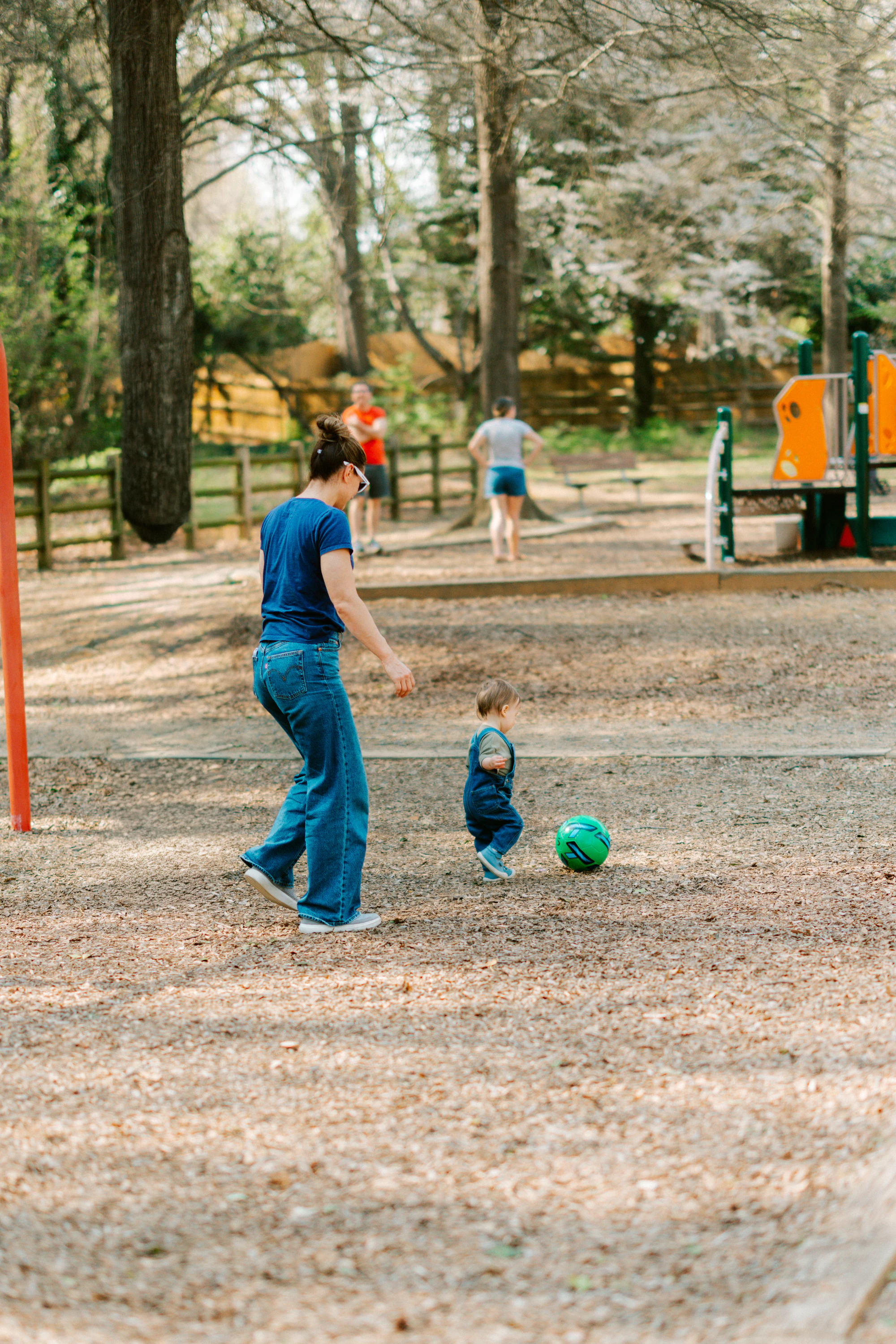 A mother playing soccer with her child in a park