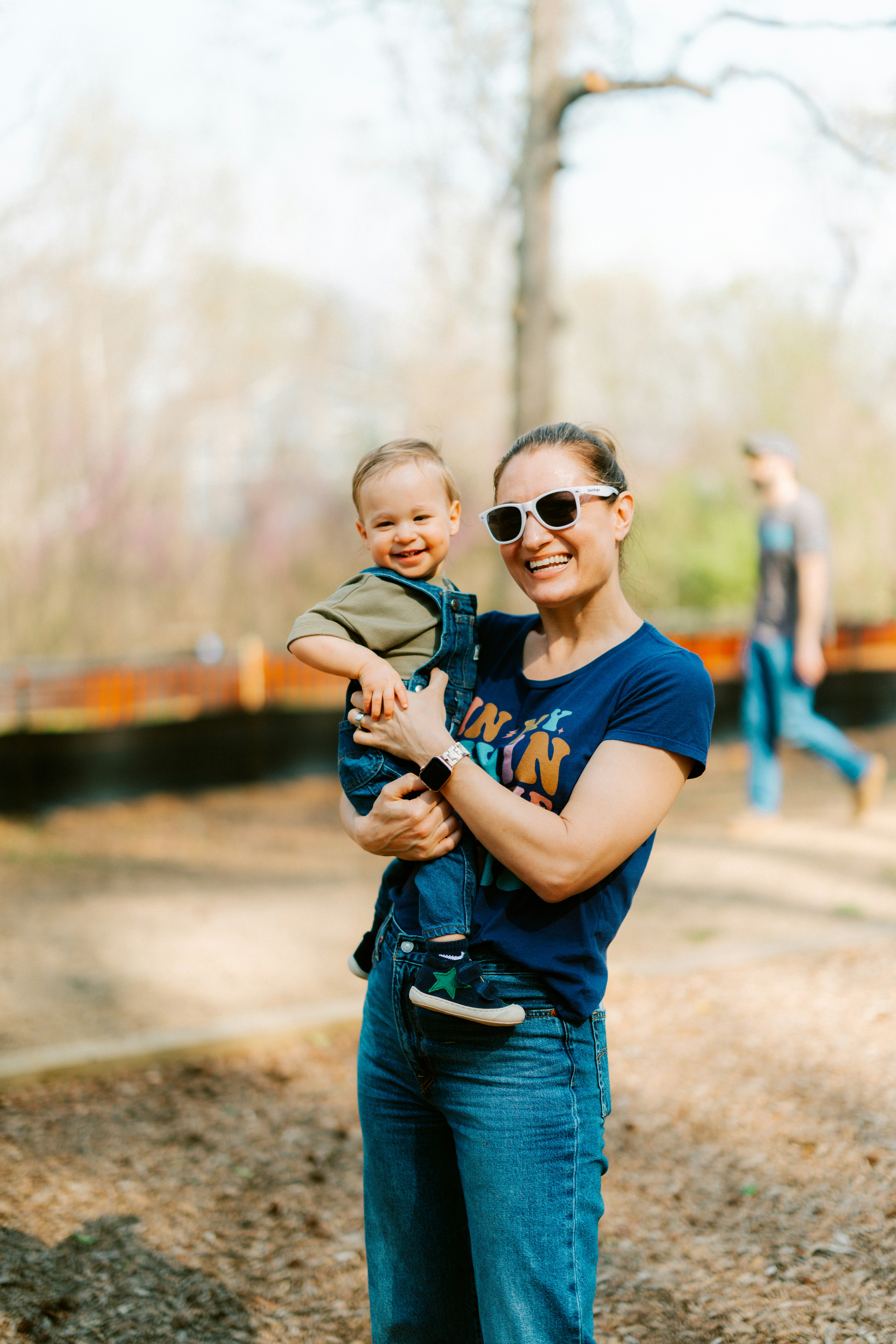 A woman holds a smiling baby outdoors