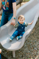 A toddler slides down a playground slide.