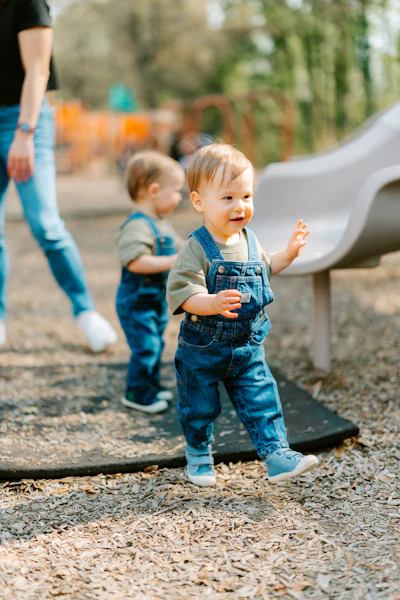 Two toddlers in denim dungarees at a playground