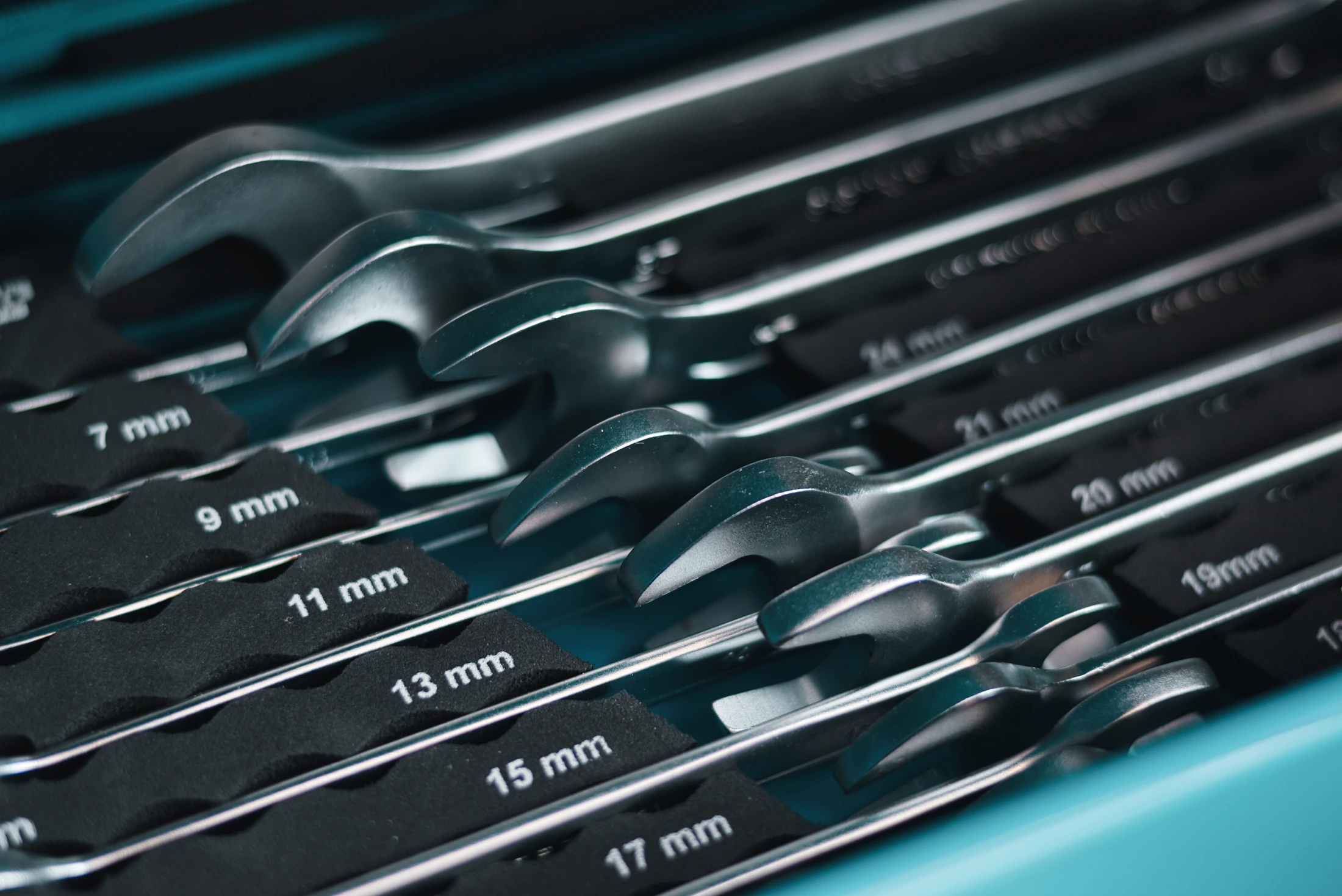 Organized set of metal combination wrenches arranged by size inside a workshop tool drawer