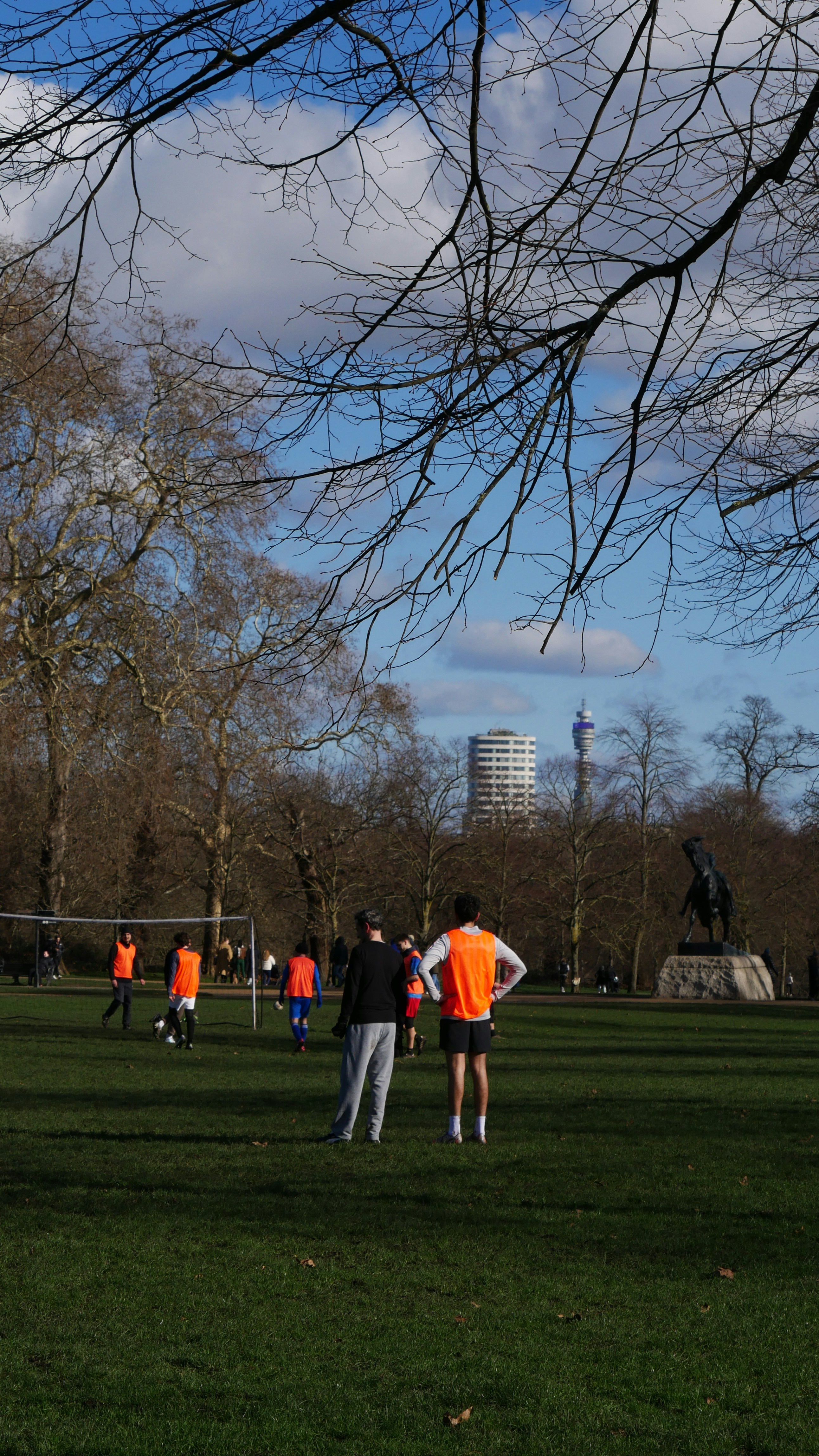 People playing soccer in a park with trees