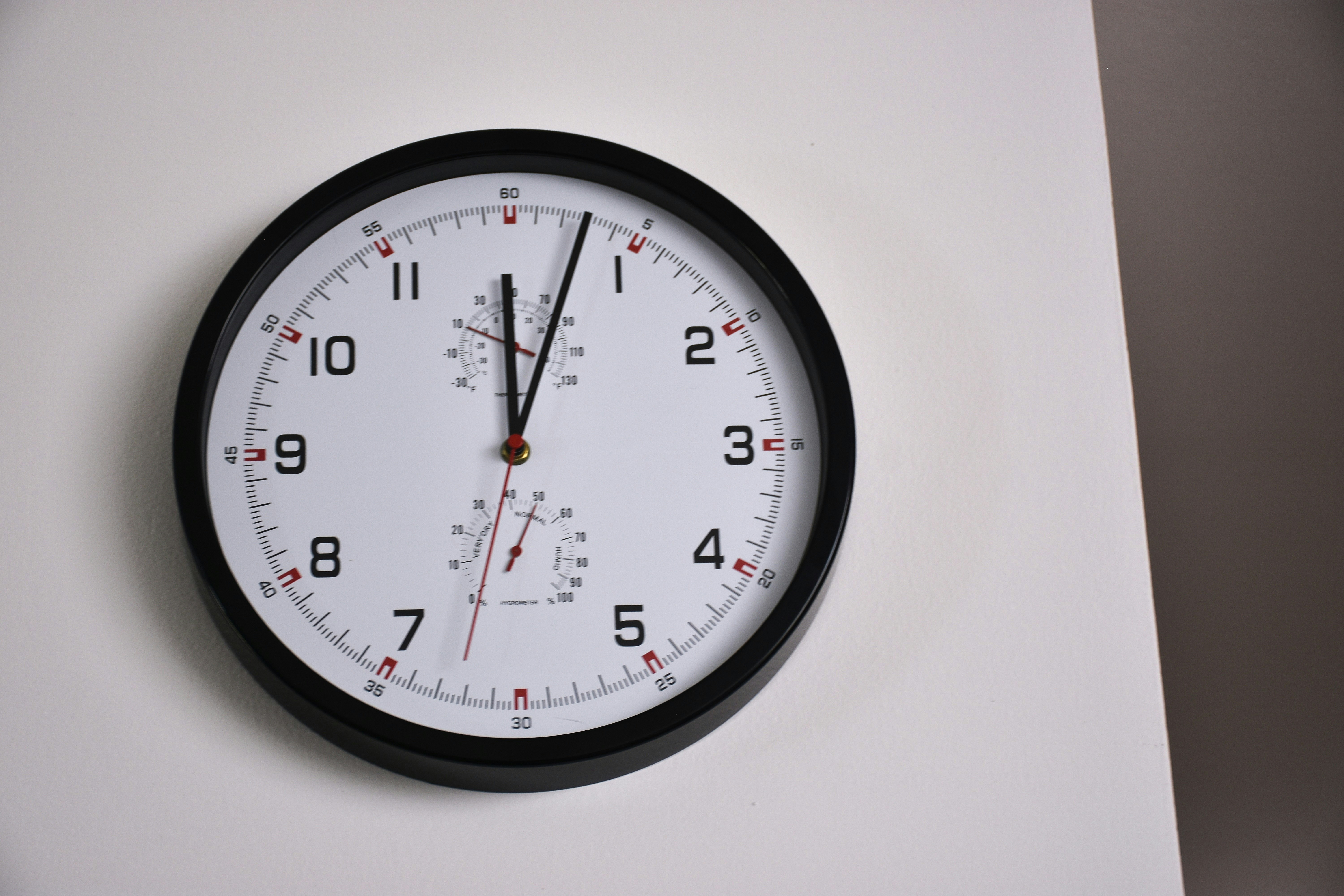Eine schwarz gerahmte Uhr an einer weißen Wand
