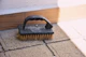 A black handled scrubbing brush on paving stones