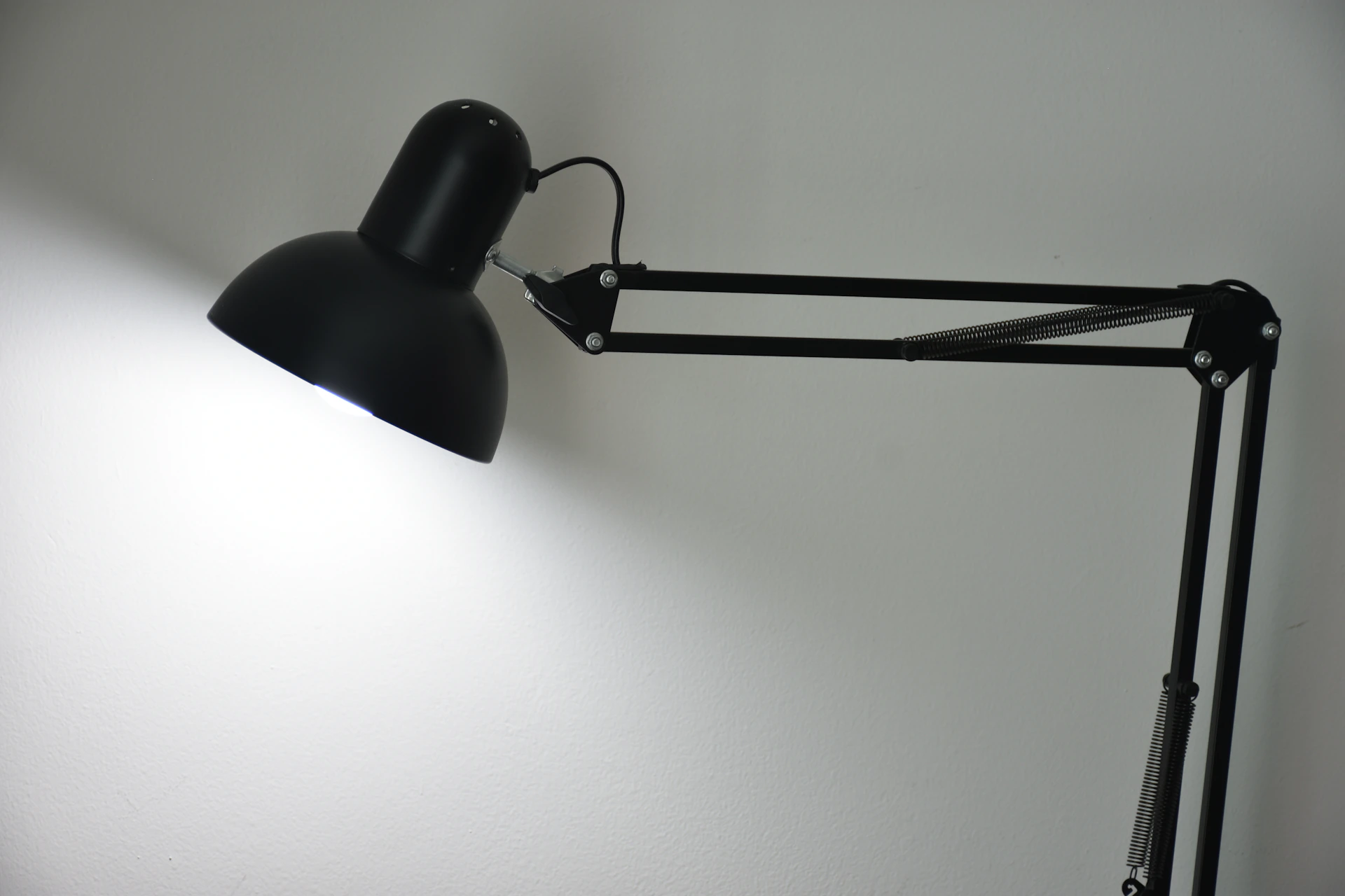 A black adjustable desk lamp shines light