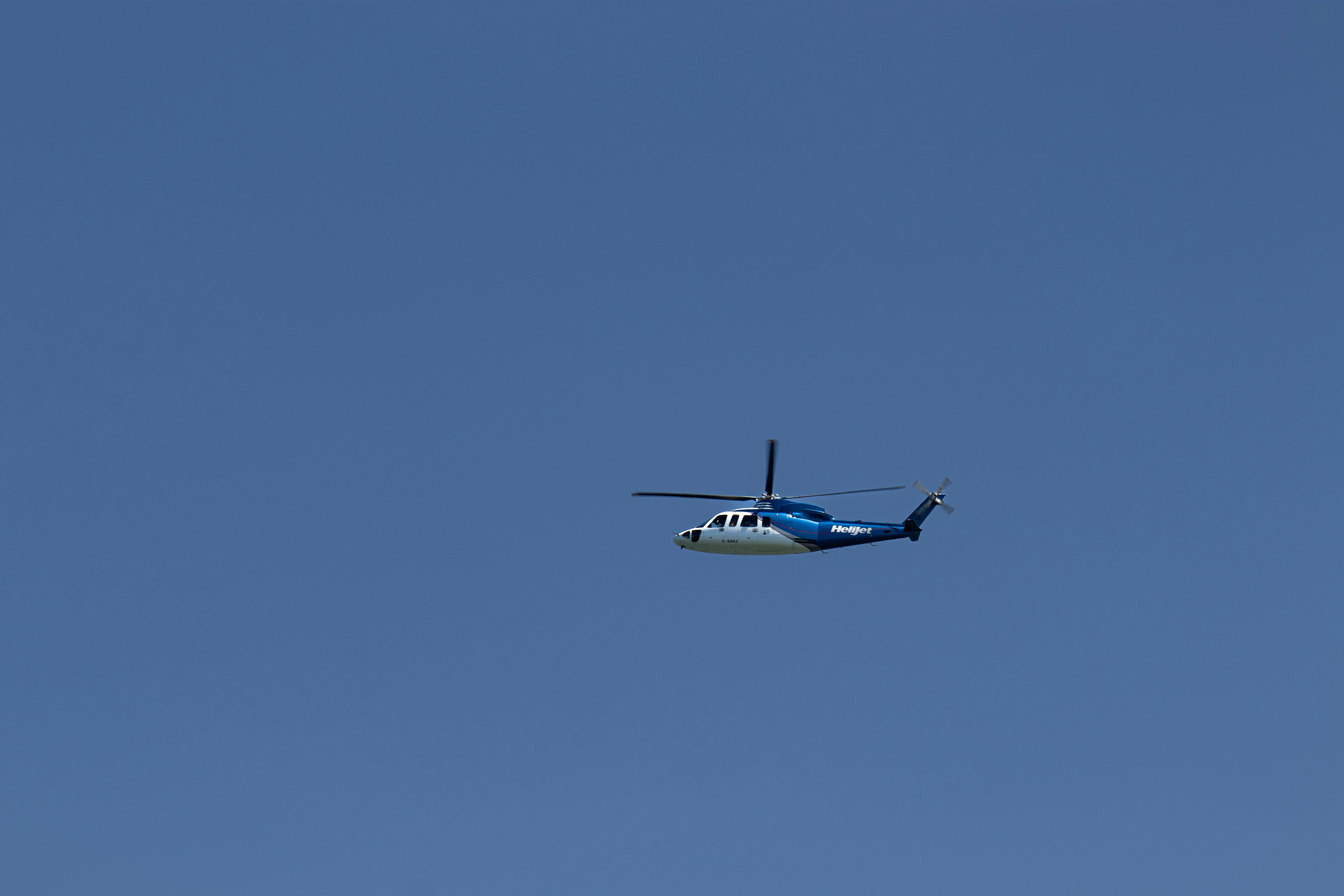 Un hélicoptère bleu et blanc volant dans un ciel bleu clair.