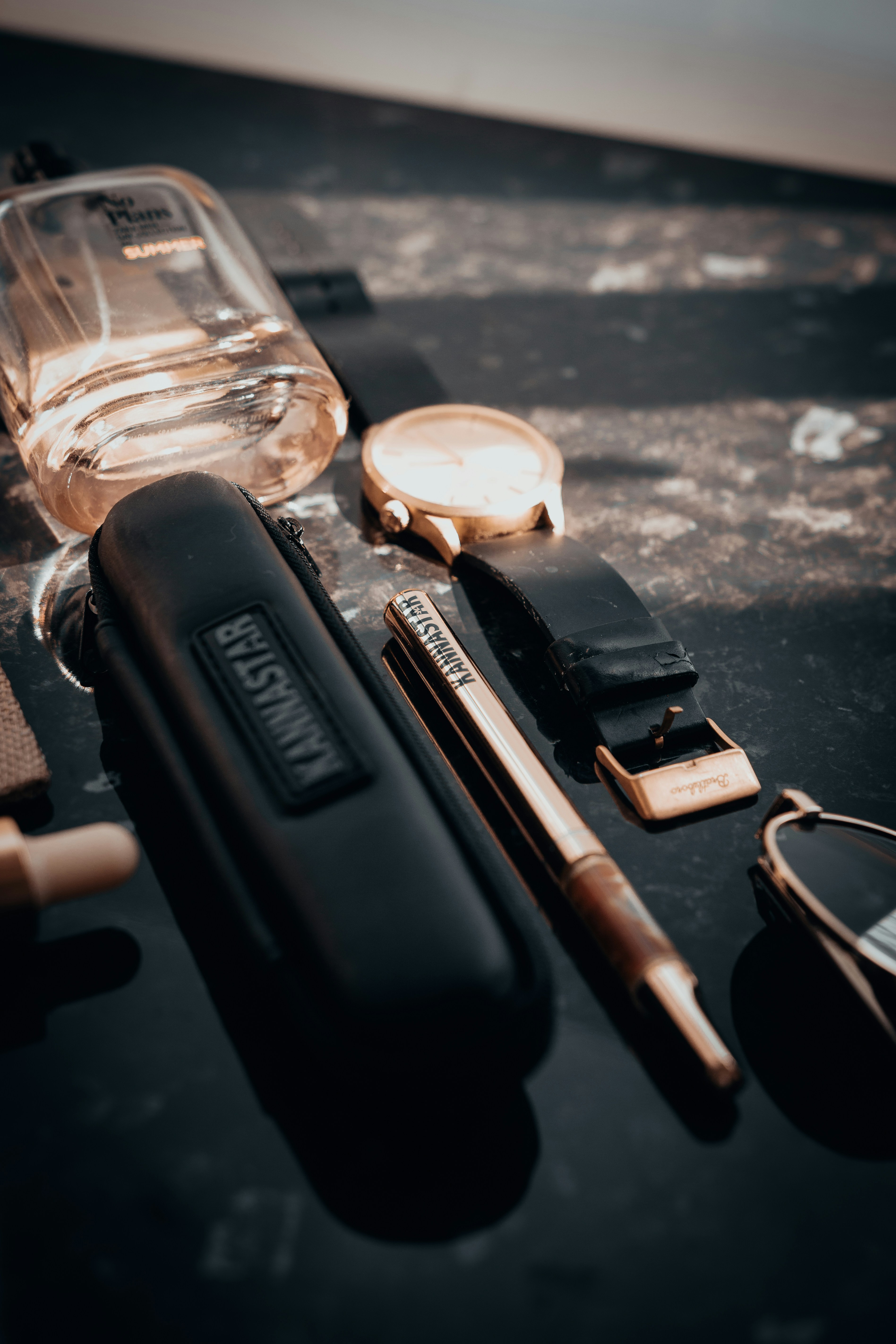 A collection of men's accessories on a dark surface.