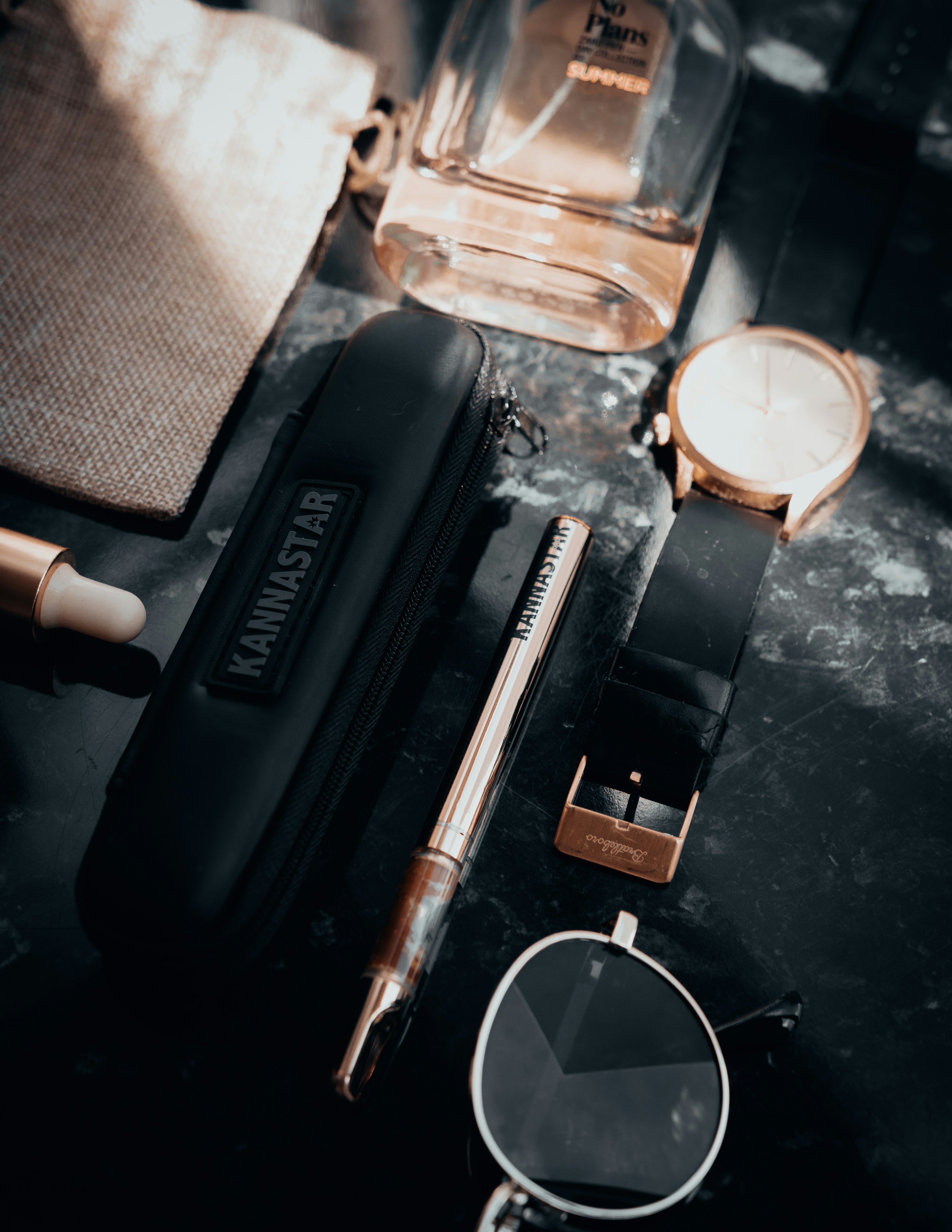 Flat lay of luxury accessories including watch and perfume.