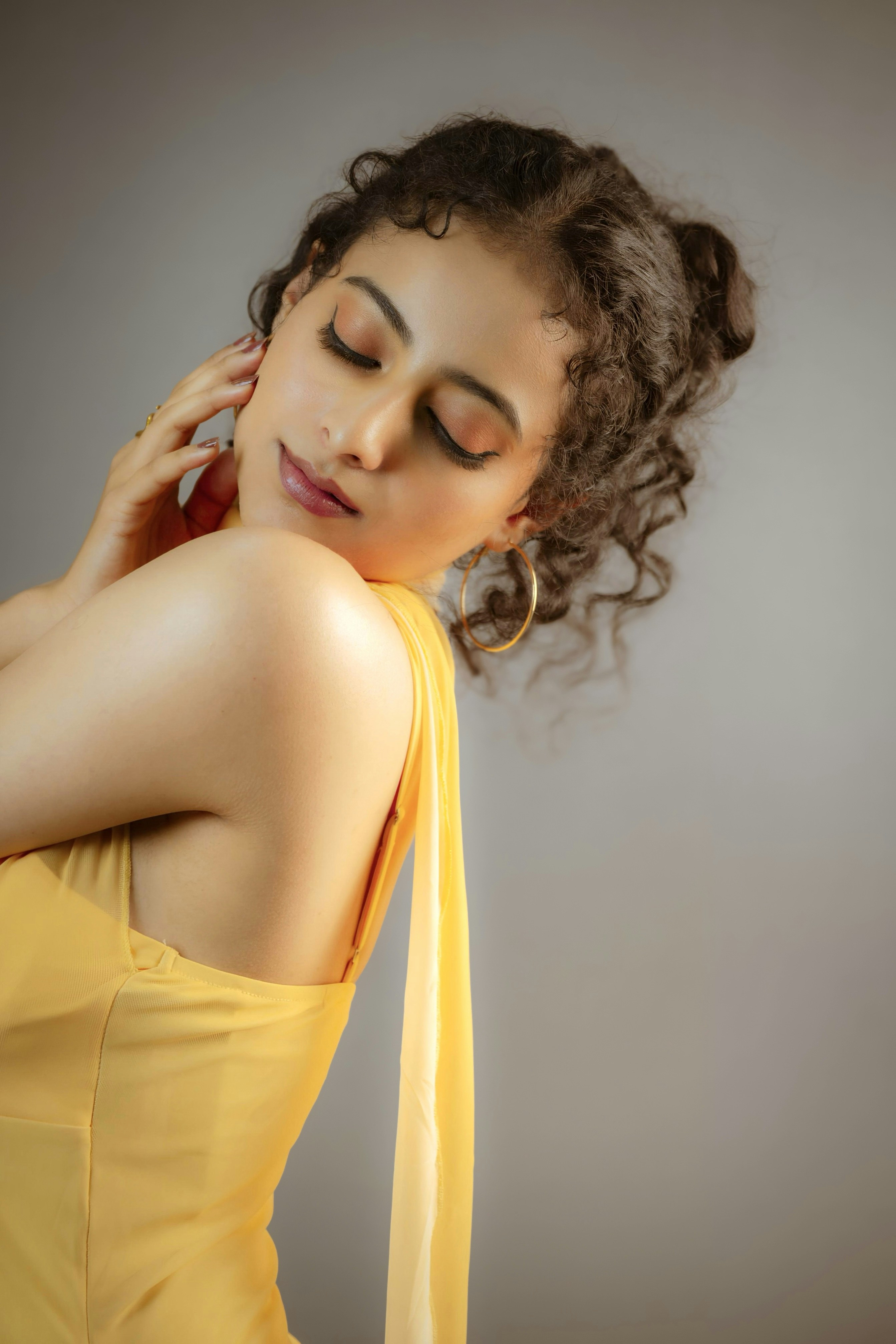 A woman in a yellow dress with eyes closed