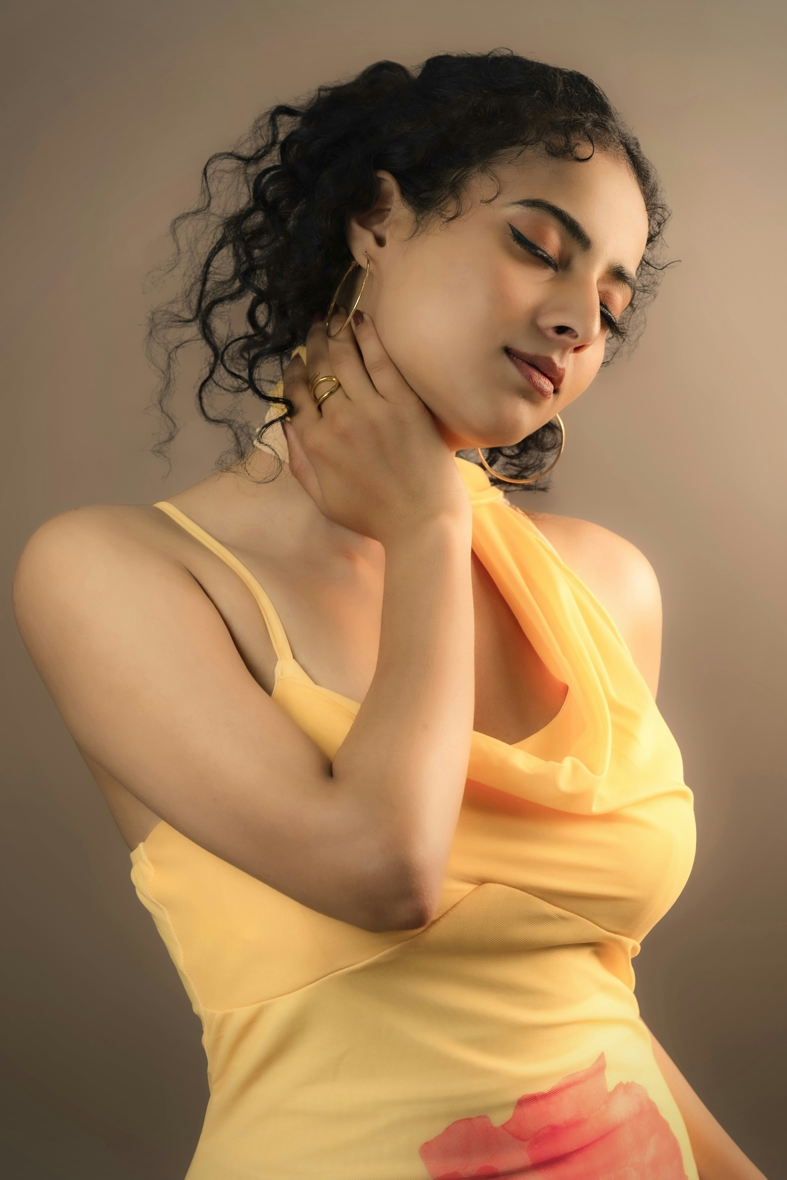 A woman with dark curly hair in a yellow dress.
