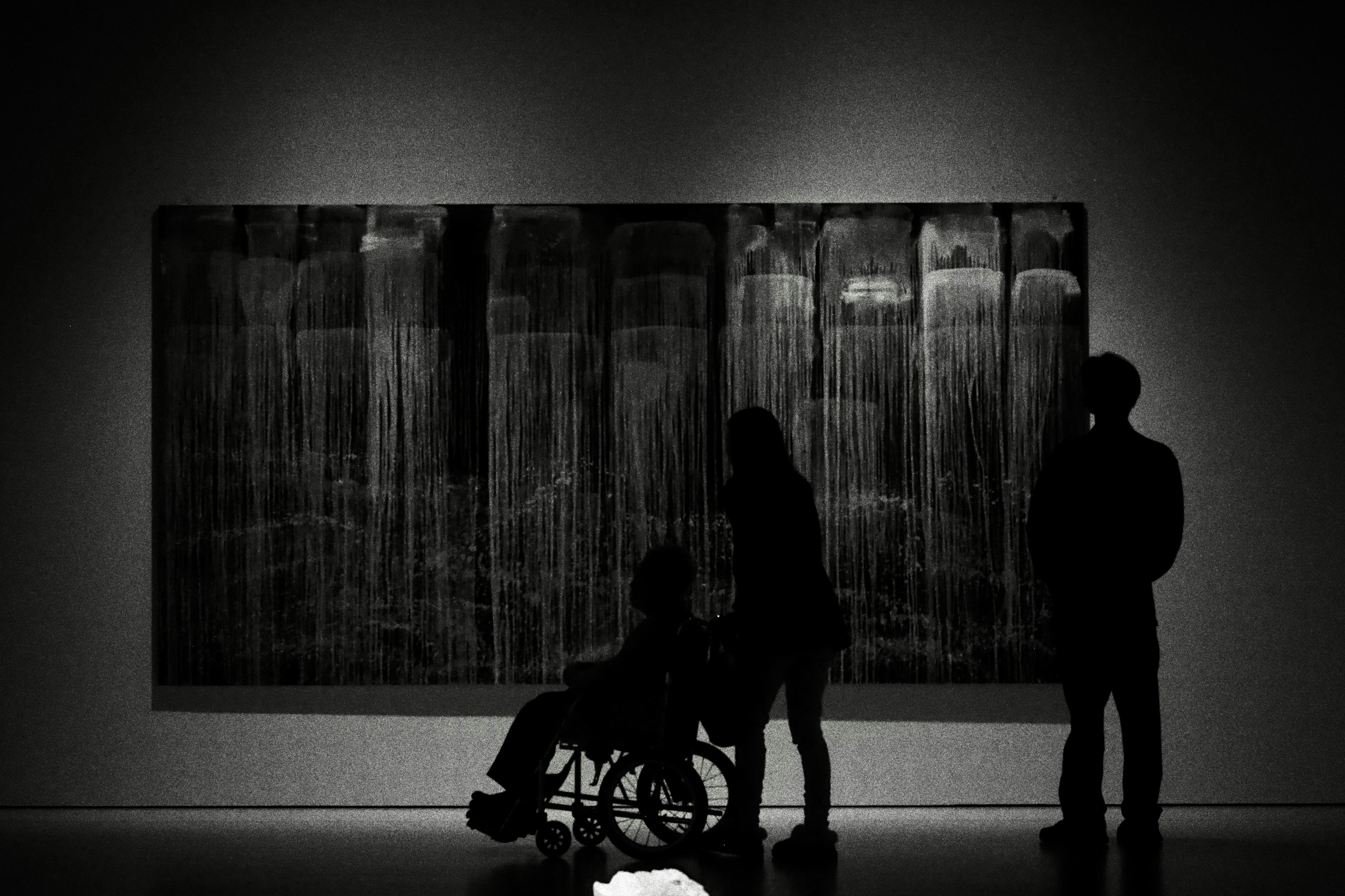 Silhouettes de personnes observant de l’art abstrait dans une galerie.