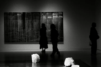 People observing abstract art in a dimly lit gallery.