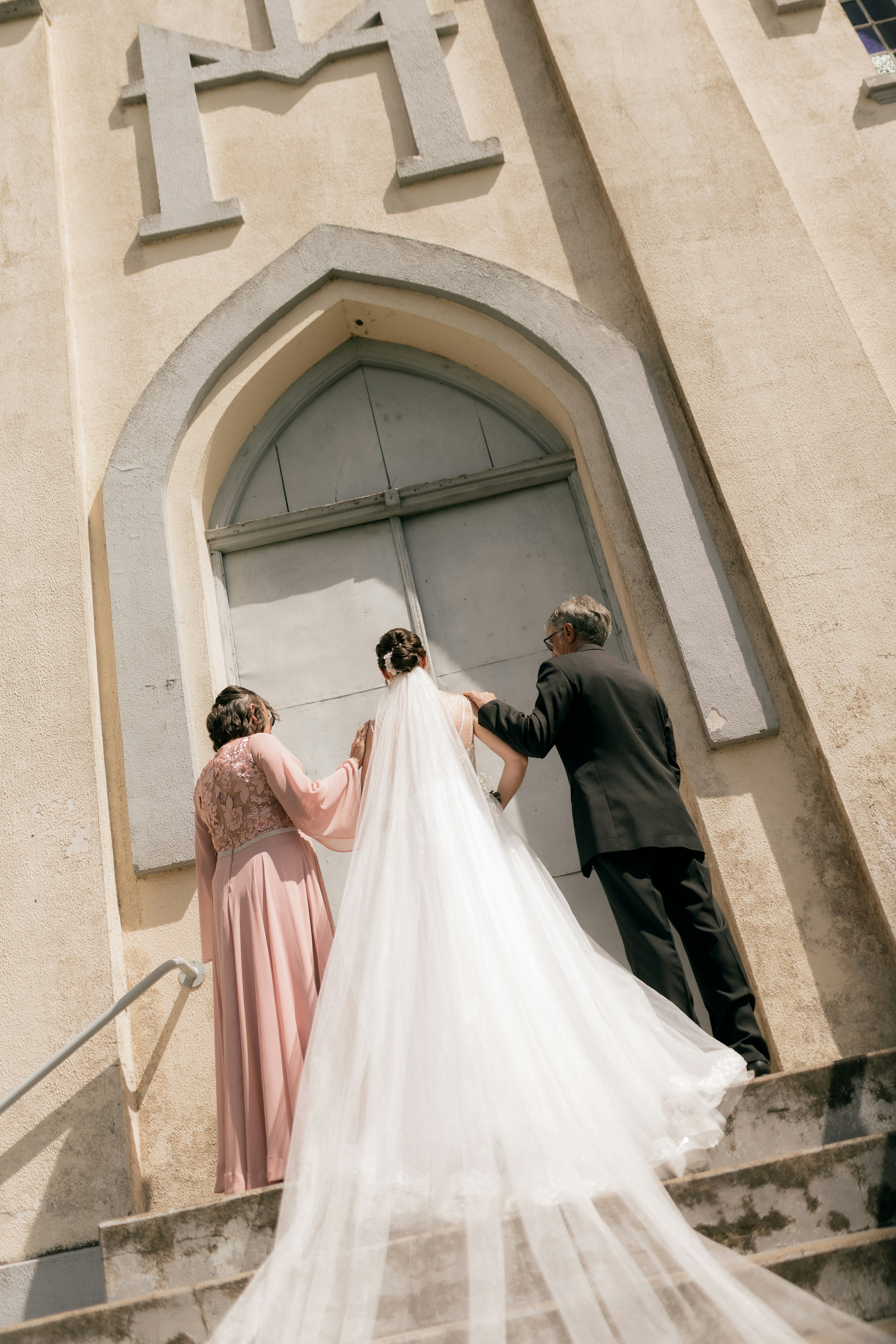 Bride and parents walk up church steps