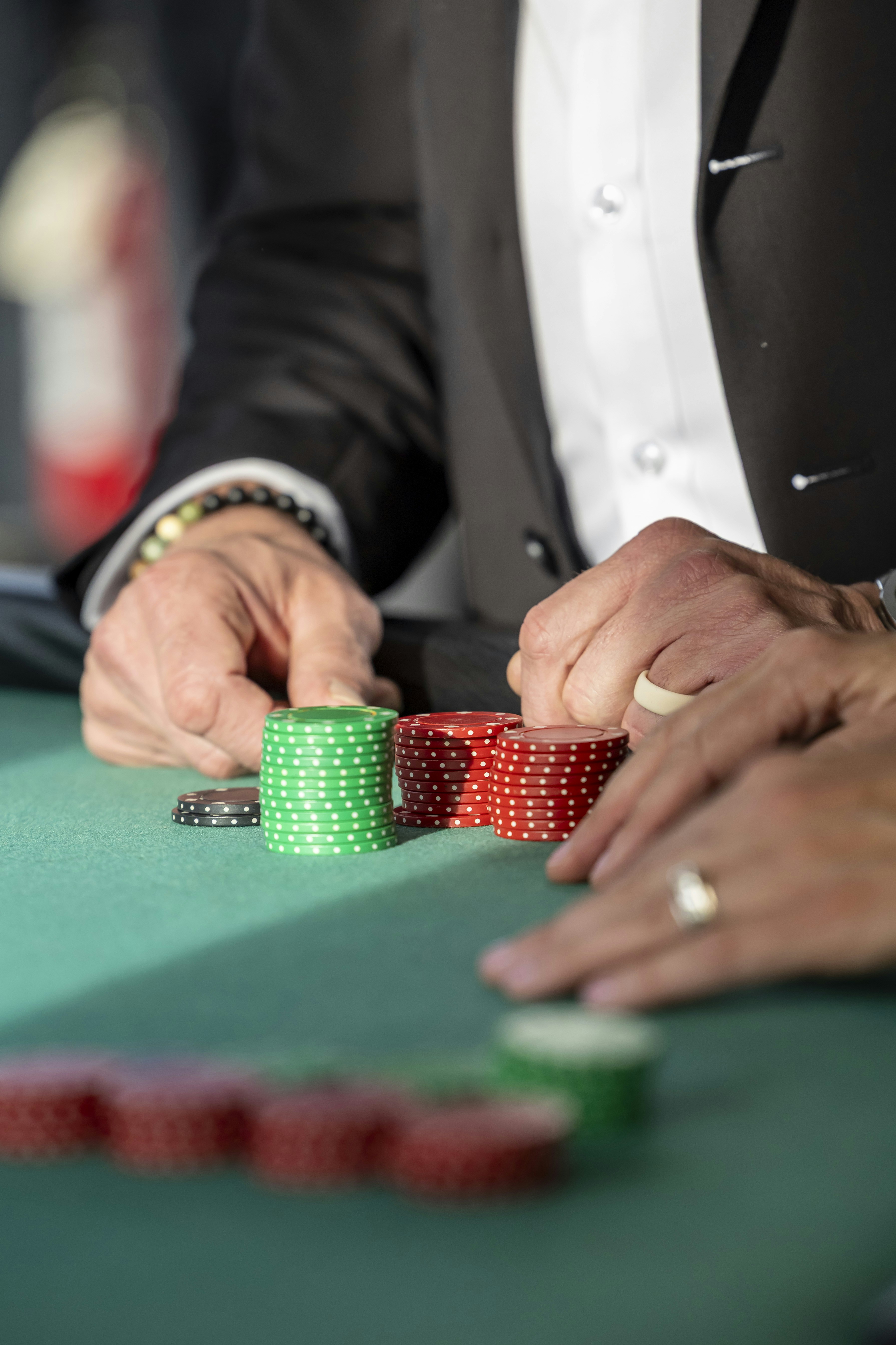 Hands reaching for poker chips on a green table
