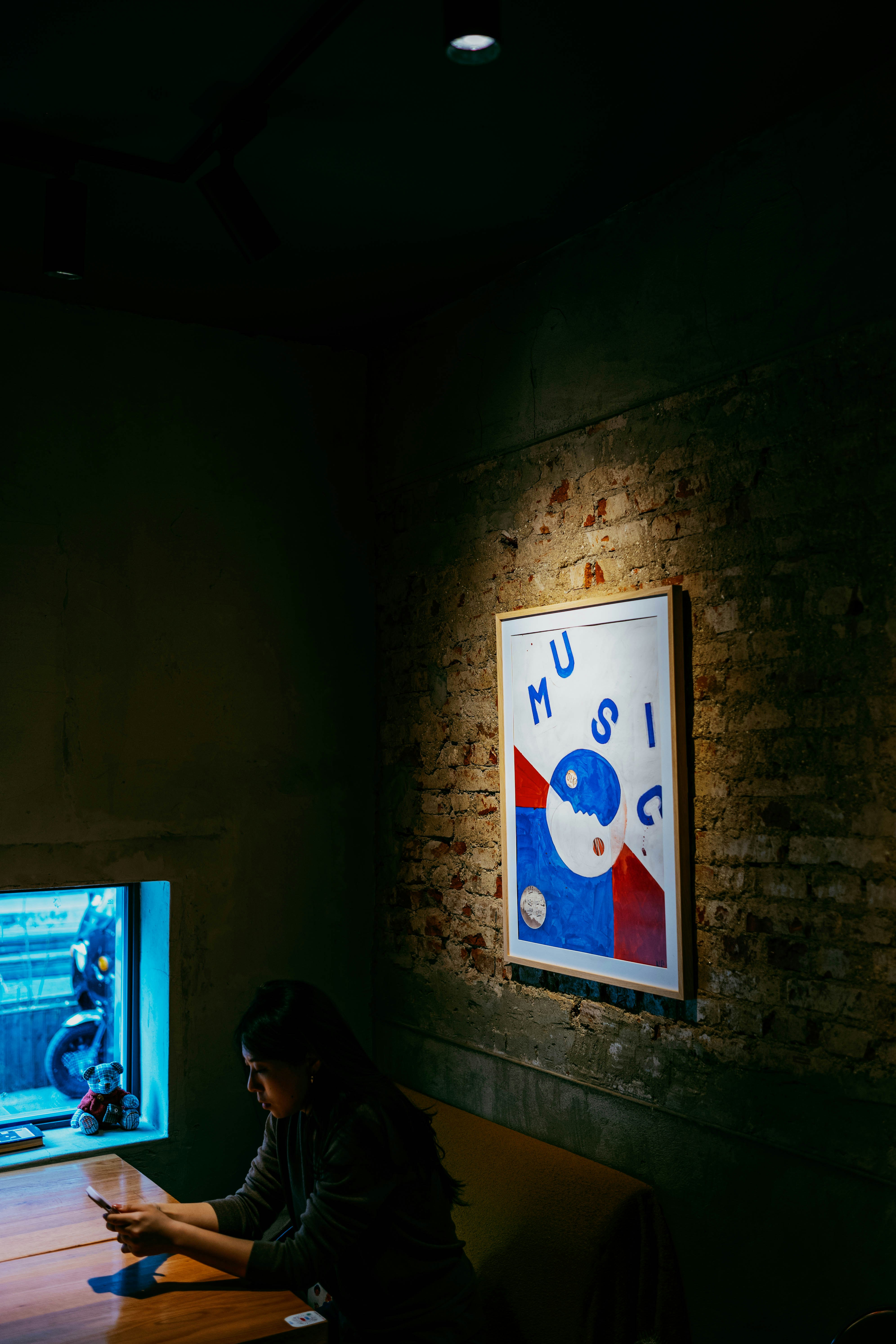 Donna che legge a un tavolo vicino a un poster musicale.