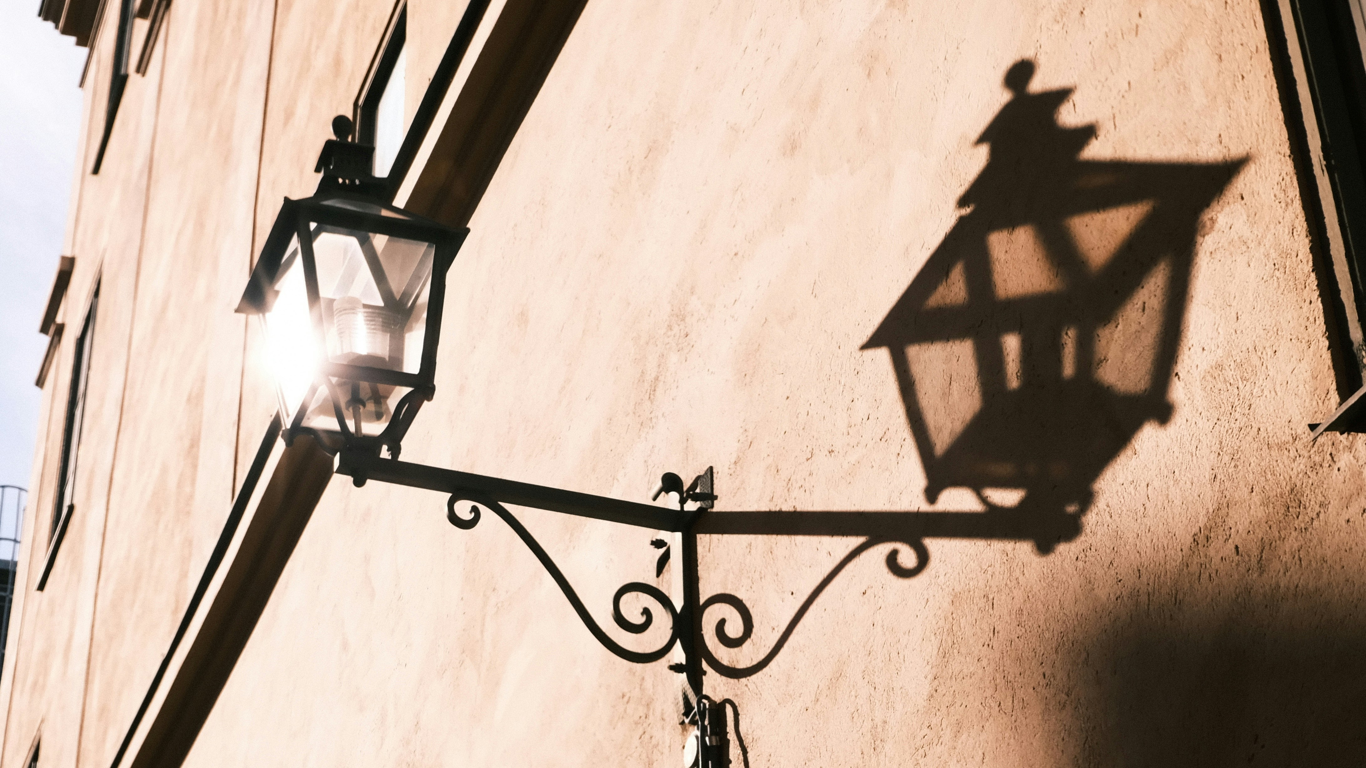 Bright vintage street lamp casting a shadow on a wall