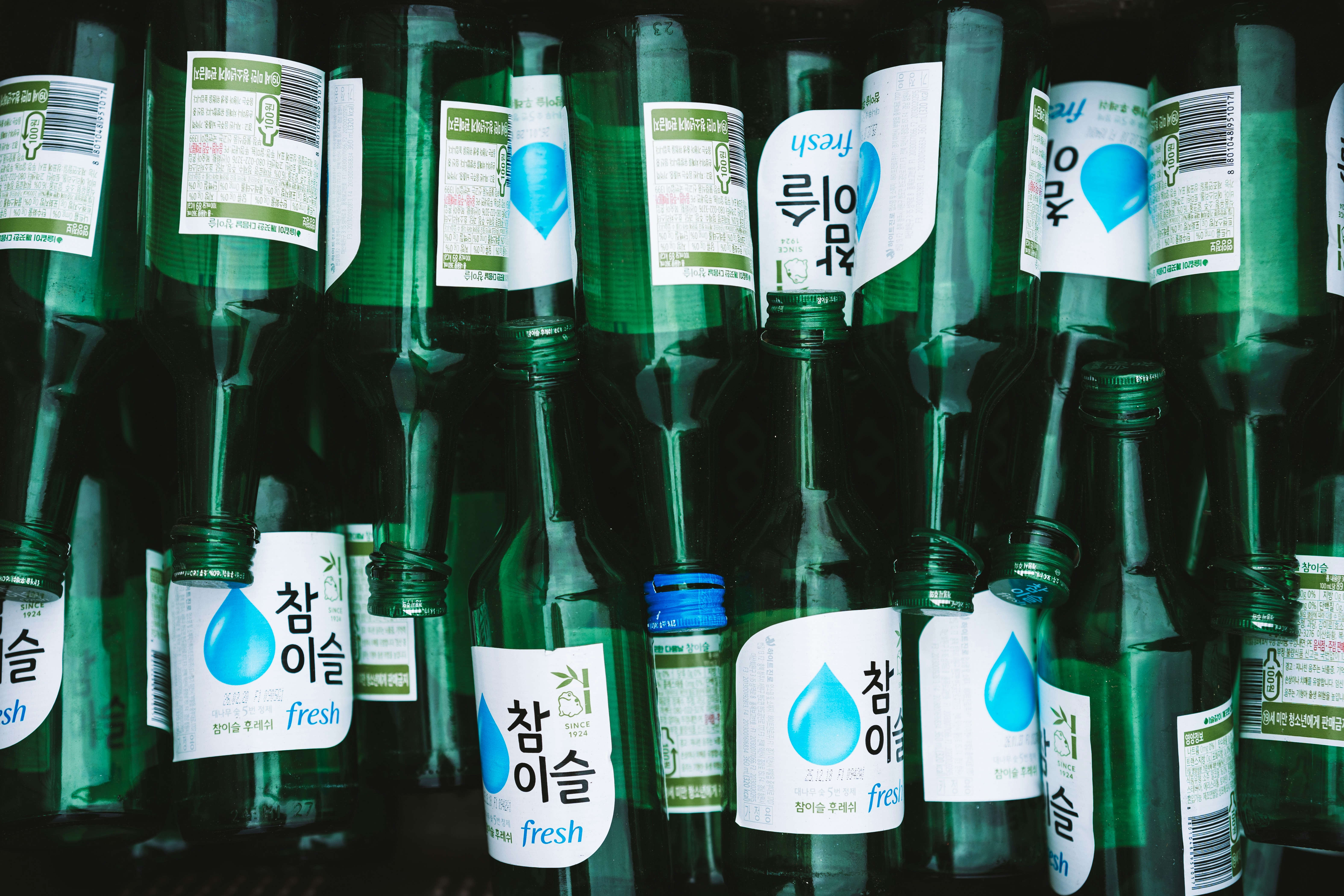 Bouteilles vertes avec des étiquettes coréennes empilées ensemble