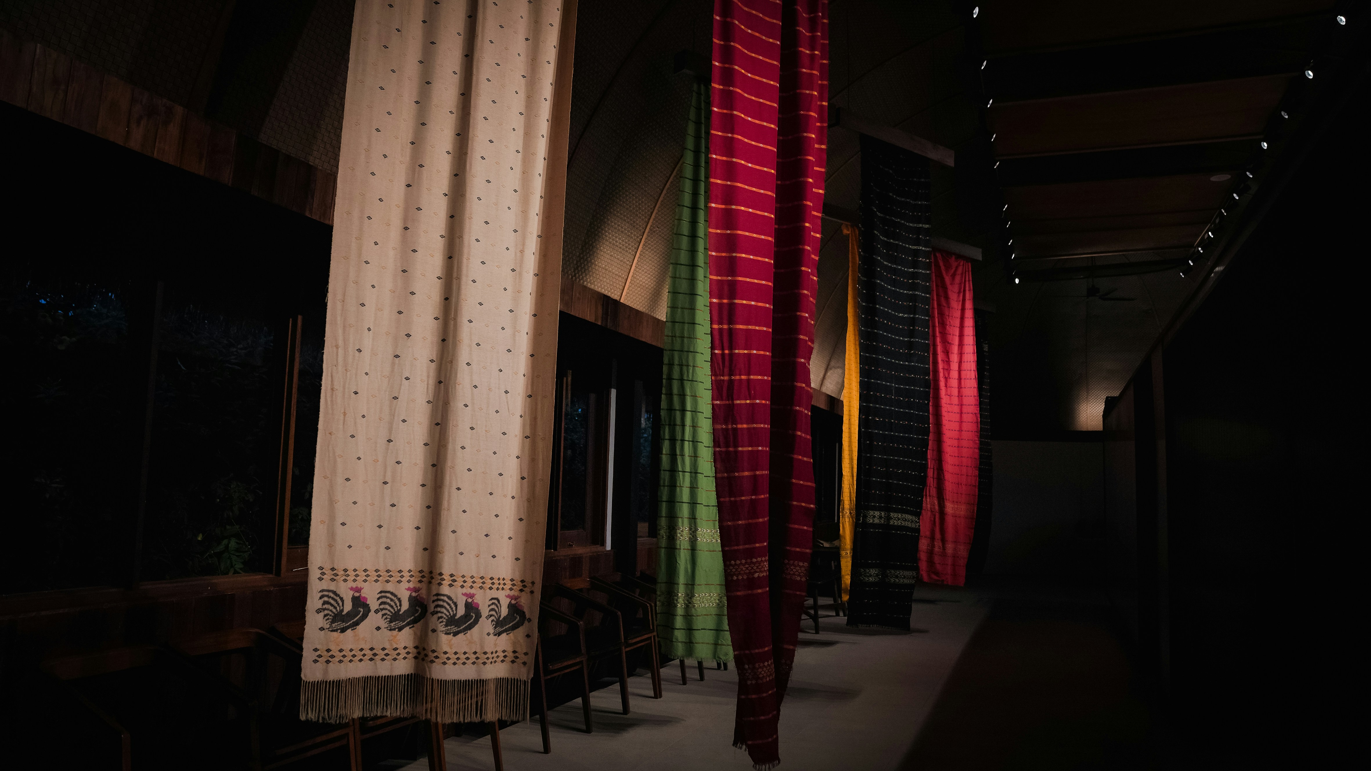 Bunte Textilien hängen in einem schwach beleuchteten Flur.