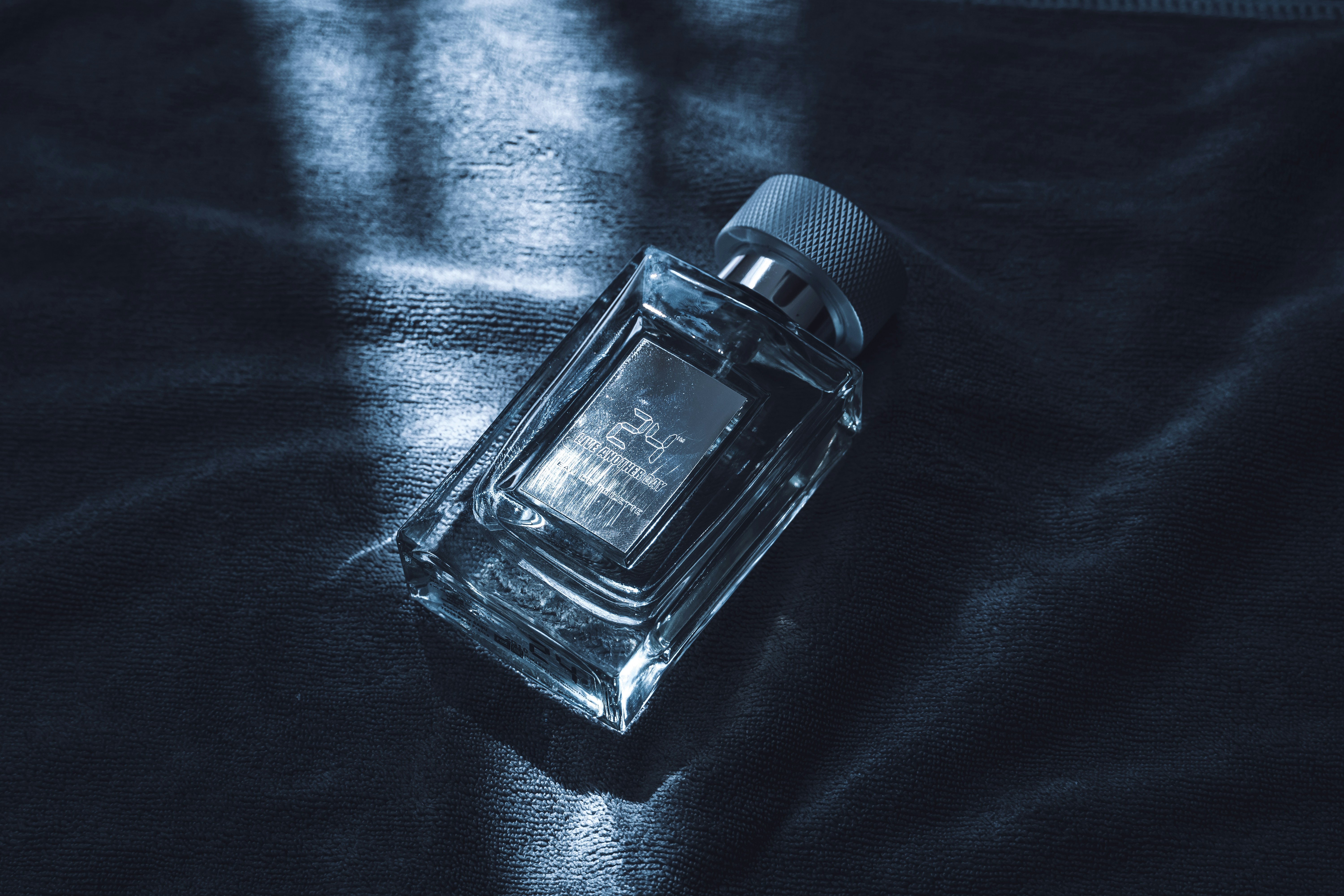 A clear glass perfume bottle with a silver cap