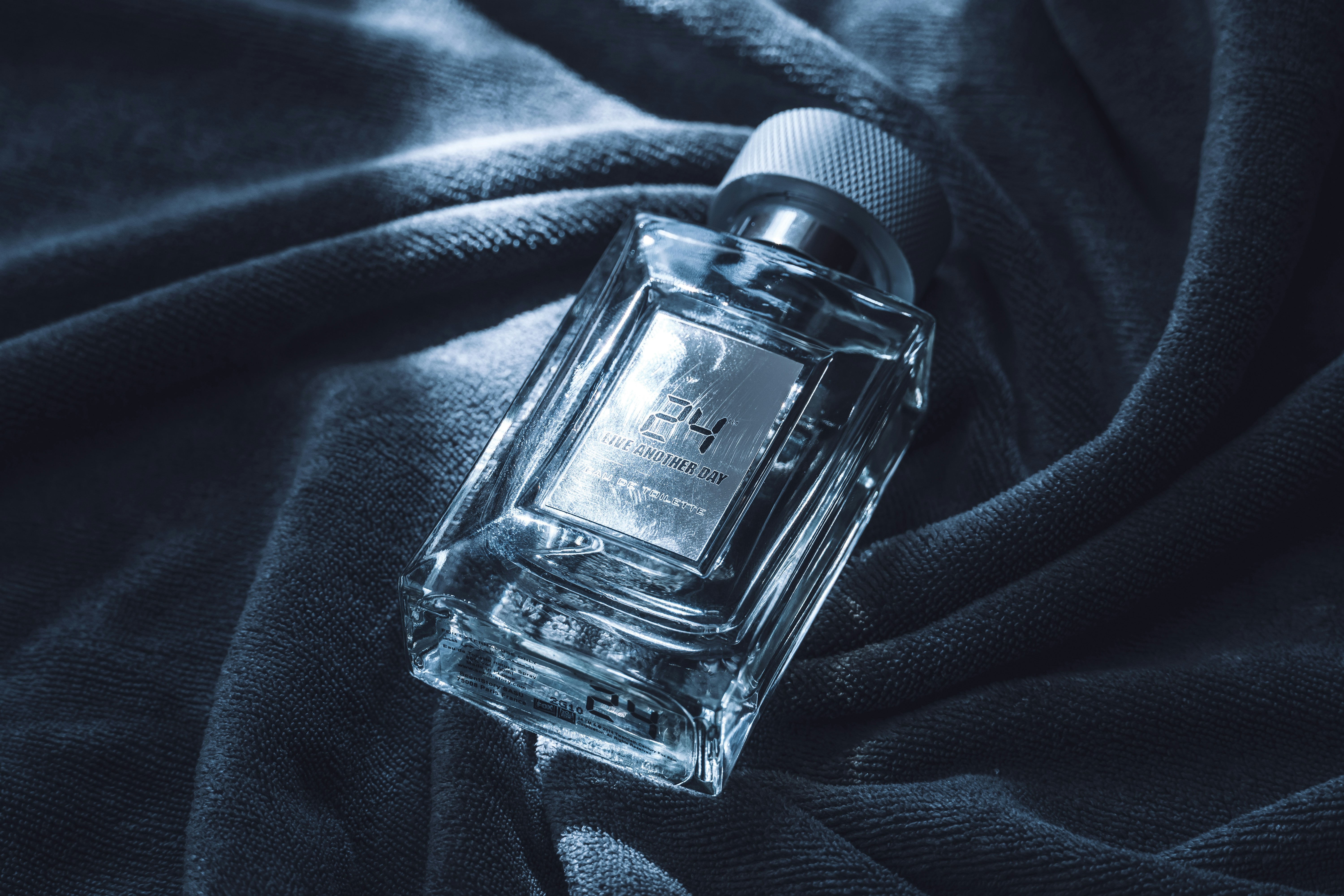 A clear glass perfume bottle on a dark cloth.