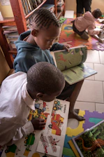 Two children reading colorful books on the floor