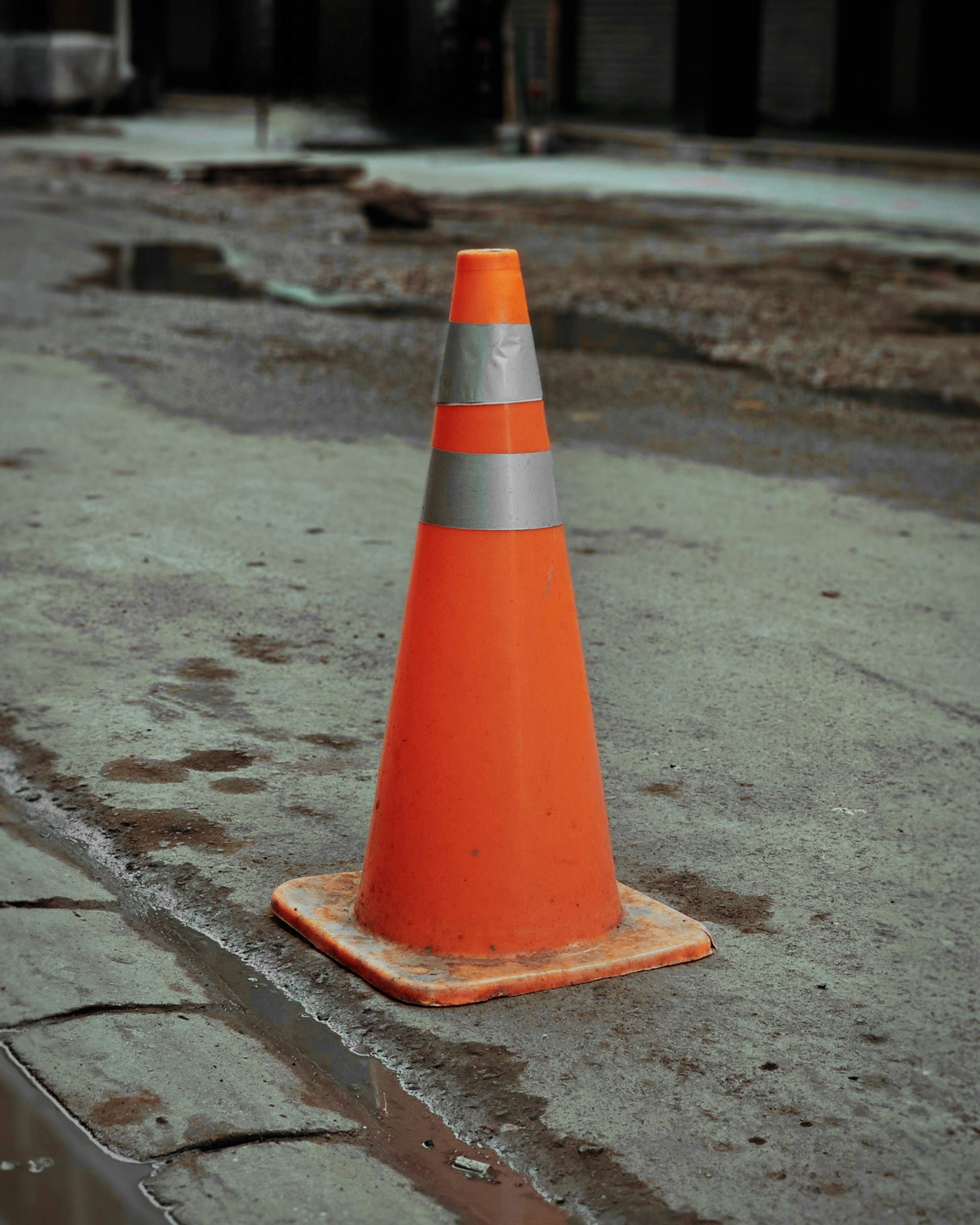 An orange traffic cone on a wet street