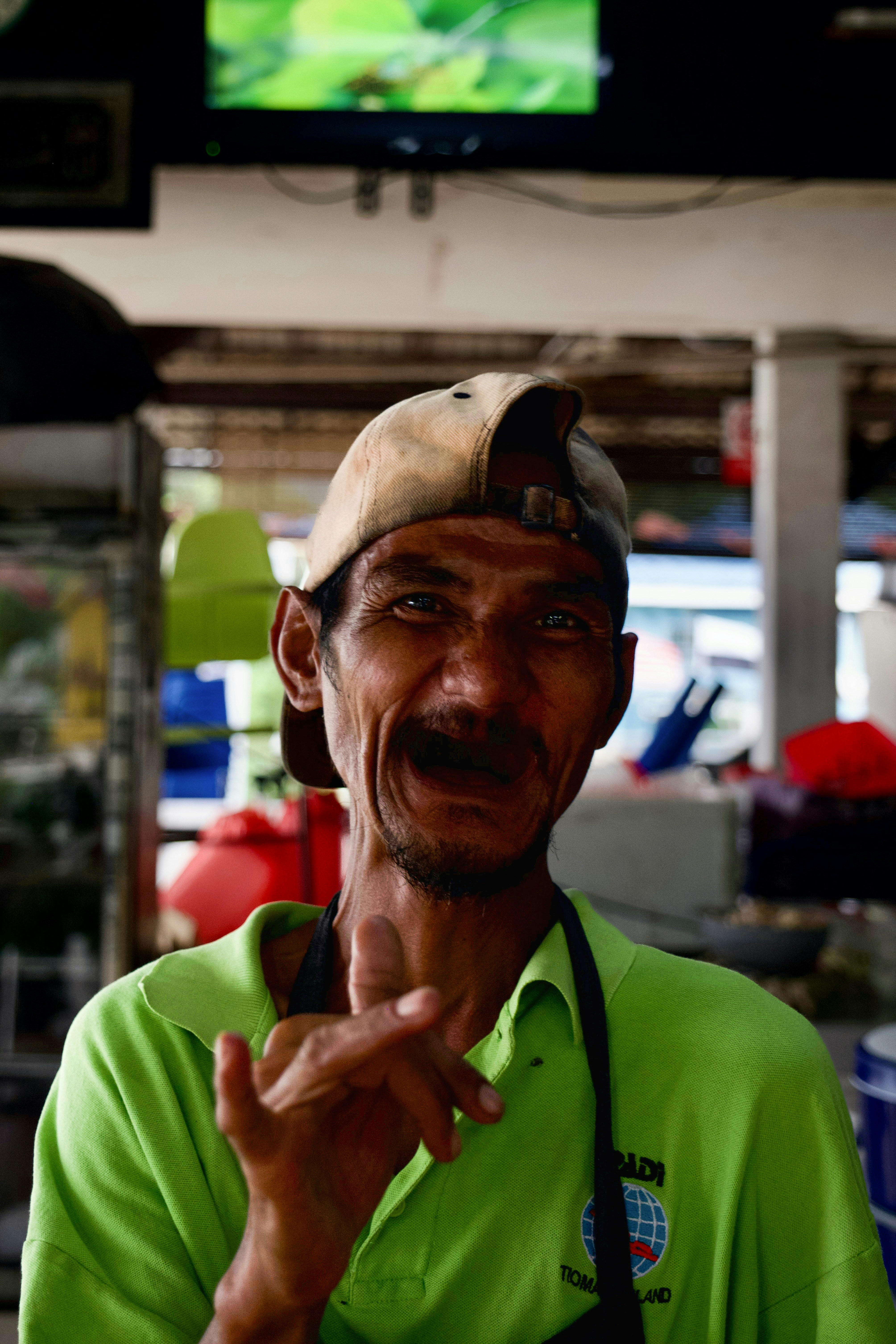 Pria berbaju hijau dan topi bisbol tersenyum.