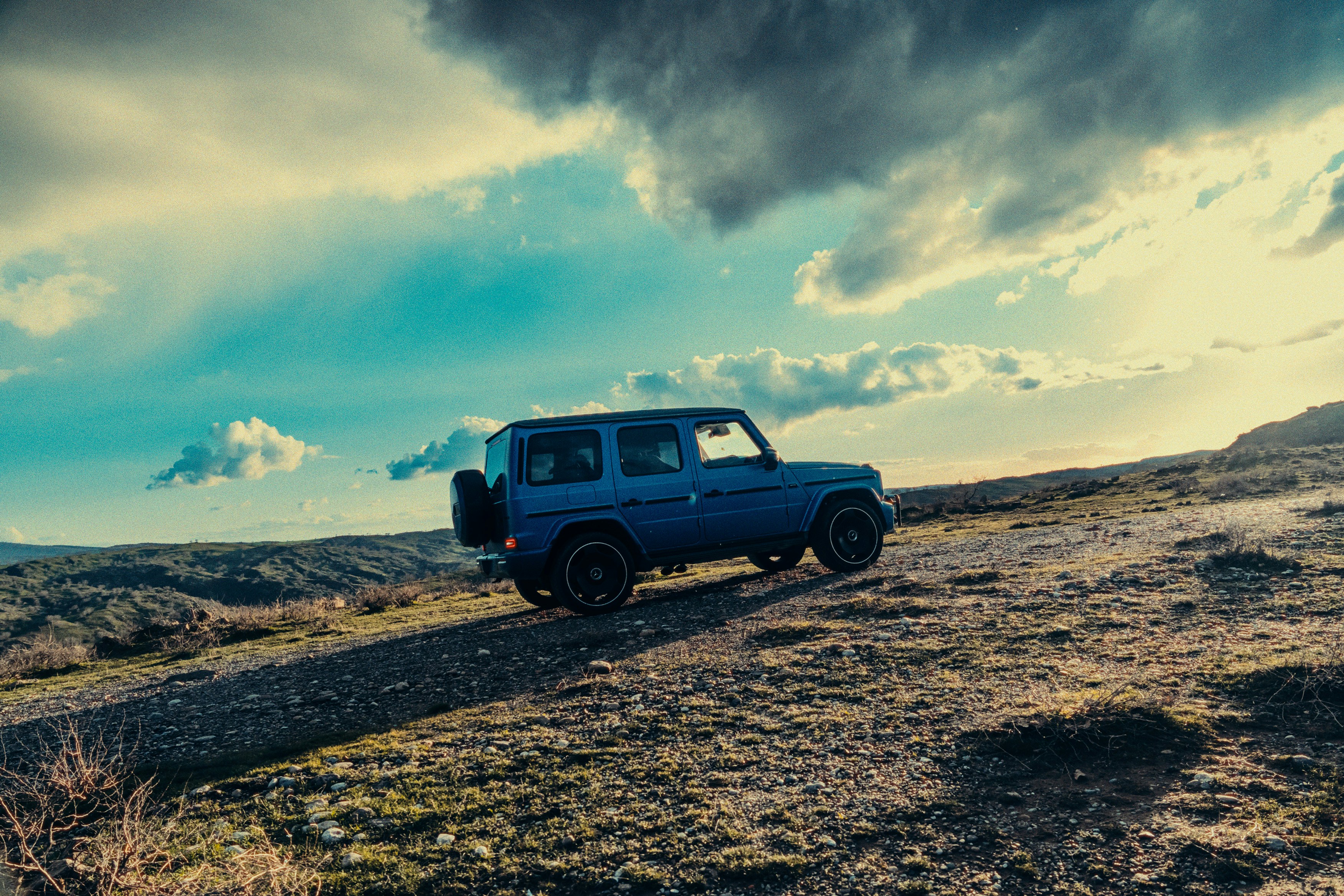 Un SUV azul circula por un paisaje rocoso y árido.