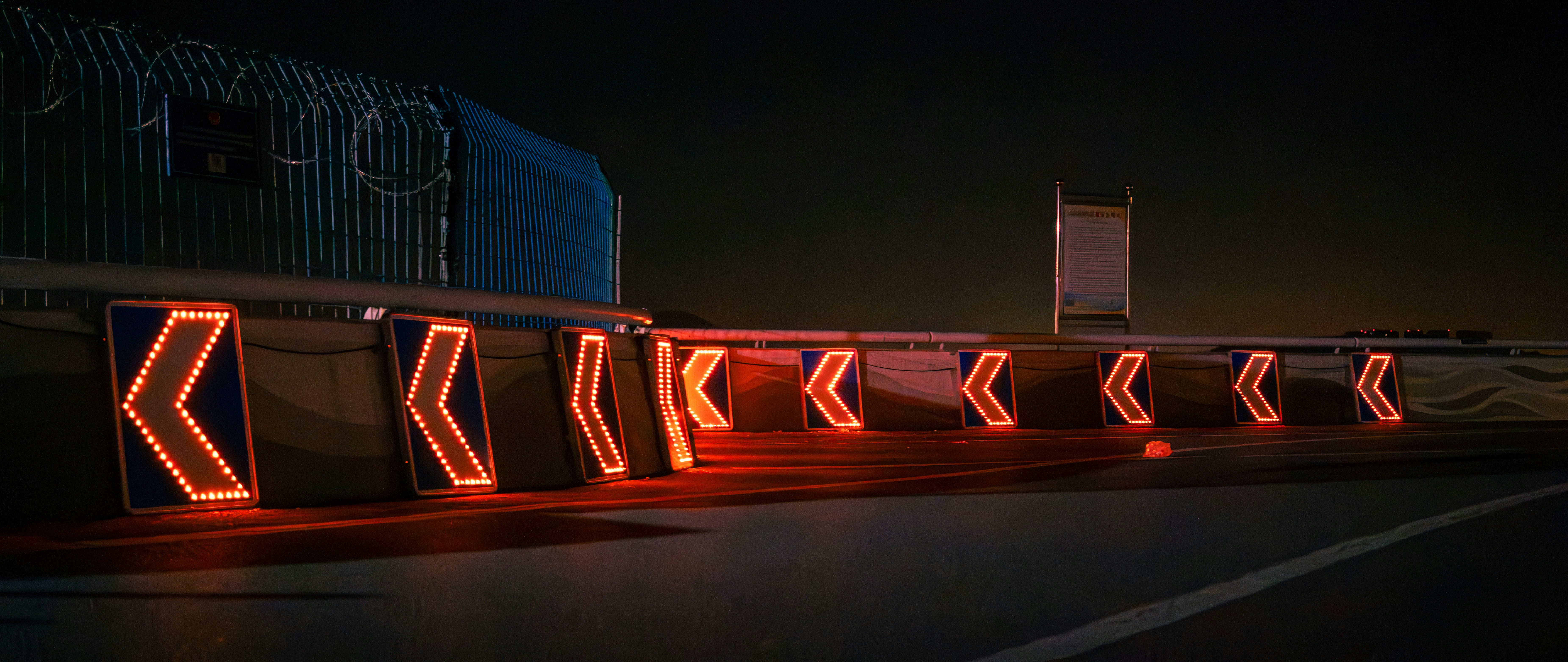 Glowing chevron signs guide traffic on a dark highway.