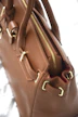 Close-up of a brown leather handbag with gold hardware.